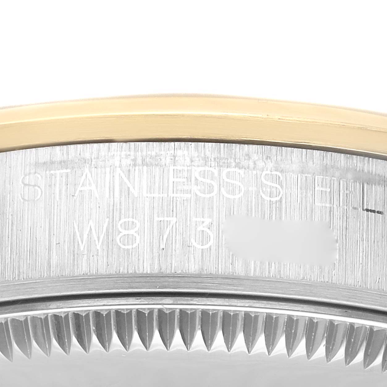 Close-up of the side view of a Rolex Mid-Size 67483 Women's Steel and Gold (two tone) Silver Dial 67483 Women's Steel and Gold (two tone) Silver Dial model watch, showing part of the bezel and the stainless steel casing with engravings.