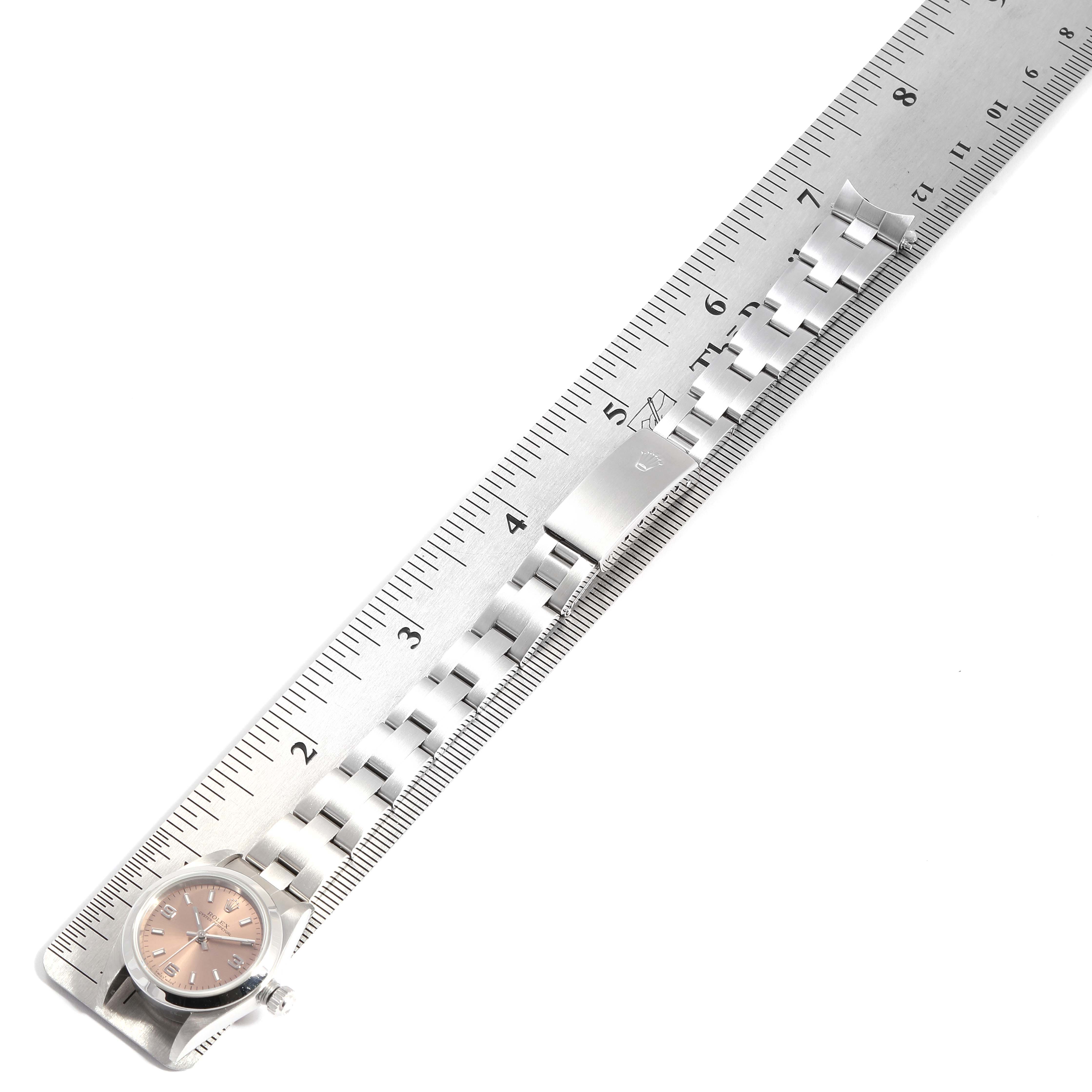 The image shows a Rolex Oyster Perpetual 76080 Women's Stainless Steel Pink Dial 76080 Women's Stainless Steel Pink Dial watch laid flat against a measuring ruler, displaying the watch face and stainless steel bracelet.
