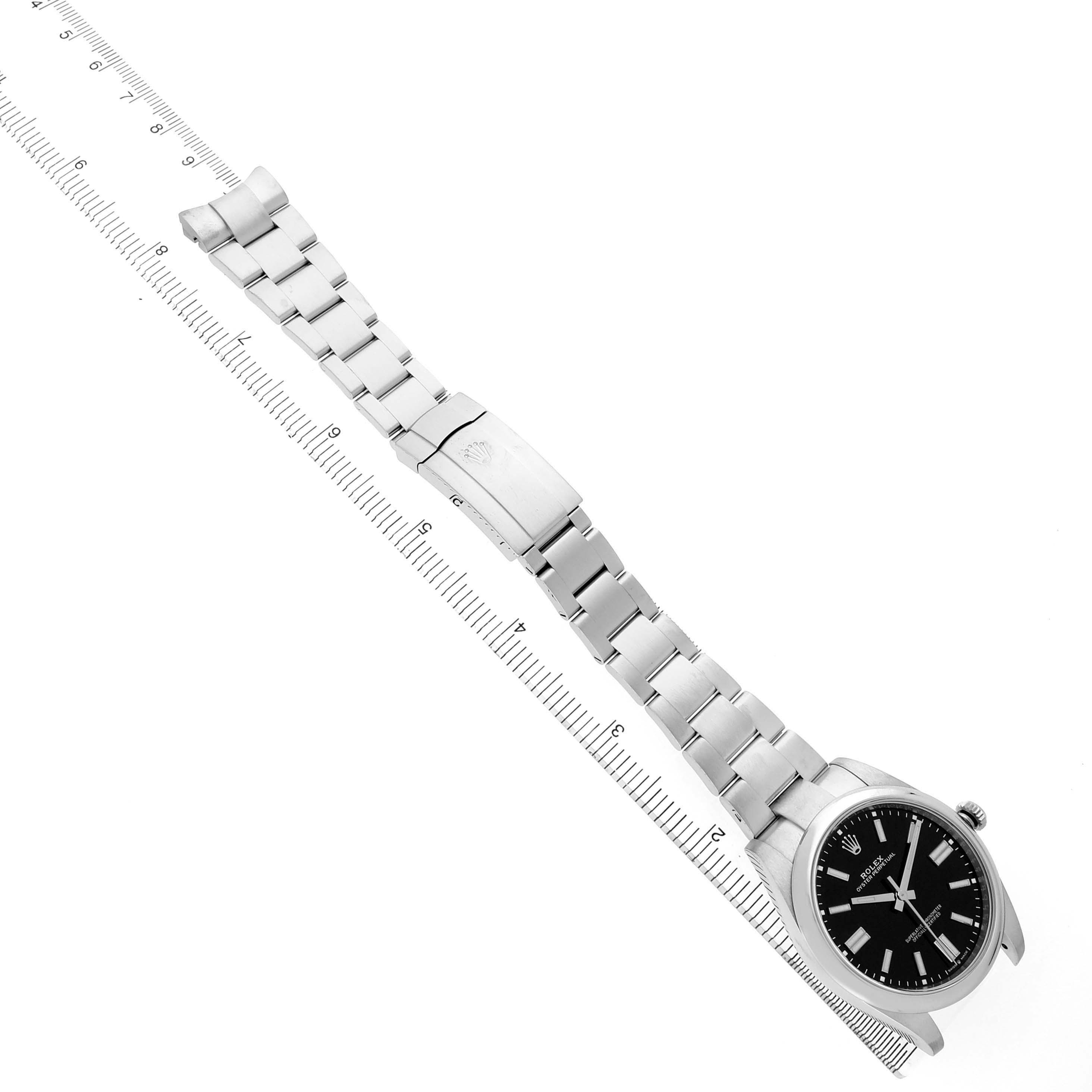 The image shows the Rolex Oyster Perpetual M124300-0002 Mens Stainless Steel Black Dial watch laid flat with an open stainless steel bracelet and the black dial visible.