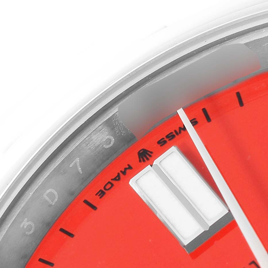The image shows a close-up of the dial of a Rolex Oyster Perpetual 124300 Men
s Stainless Steel Red Dial 124300 Men
s Stainless Steel Red Dial watch, focusing on the red face and part of the hour markers.