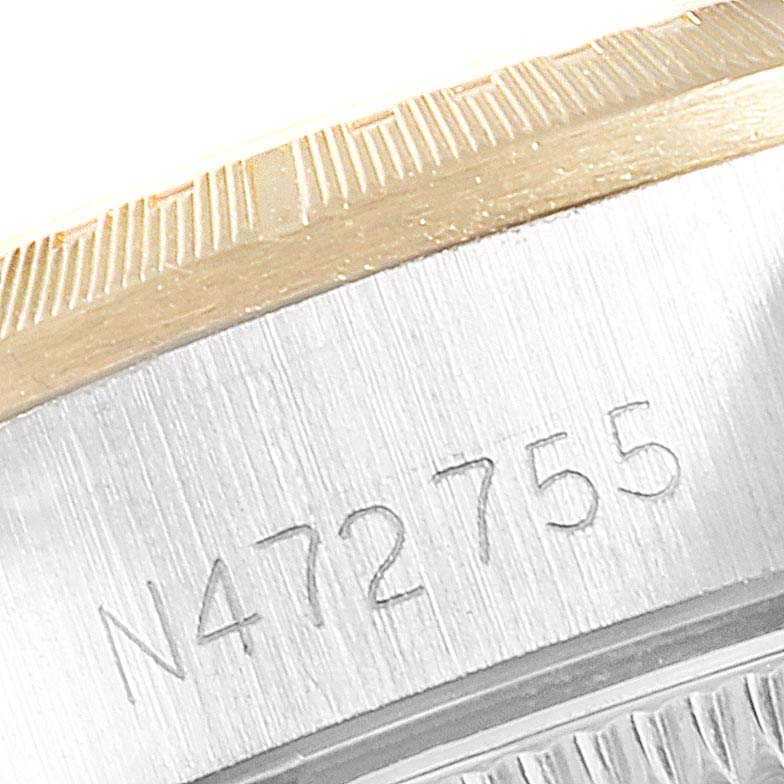 This close-up image shows the side of a Rolex Oyster Perpetual 67243 Women
s Steel and Gold (two tone) Champagne Dial 67243 Women
s Steel and Gold (two tone) Champagne Dial watch, focusing on the case and a visible serial number.