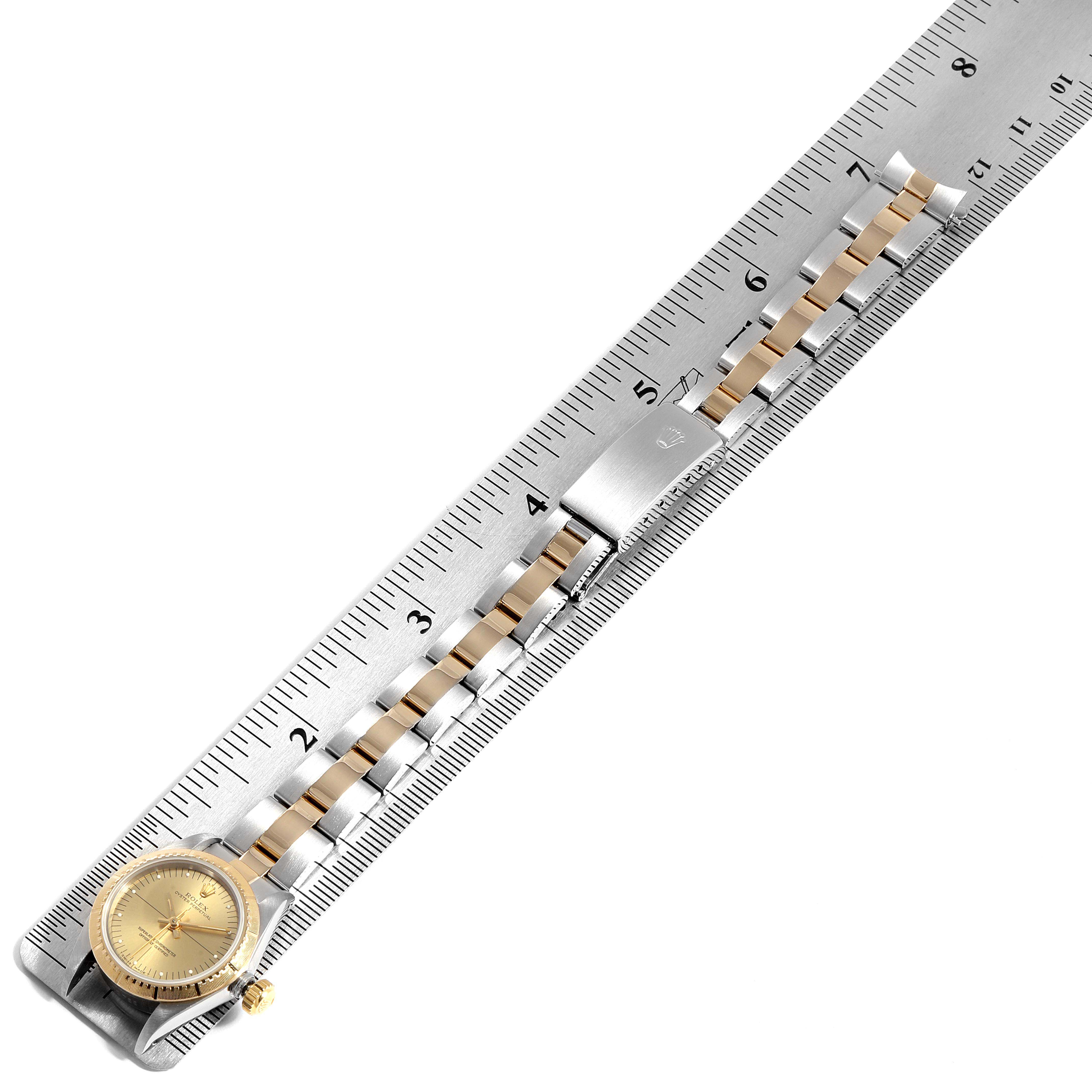 This image shows a Rolex Oyster Perpetual 67243 Women
s Steel and Gold (two tone) Champagne Dial 67243 Women
s Steel and Gold (two tone) Champagne Dial watch face and band aligned with a ruler for measurement.