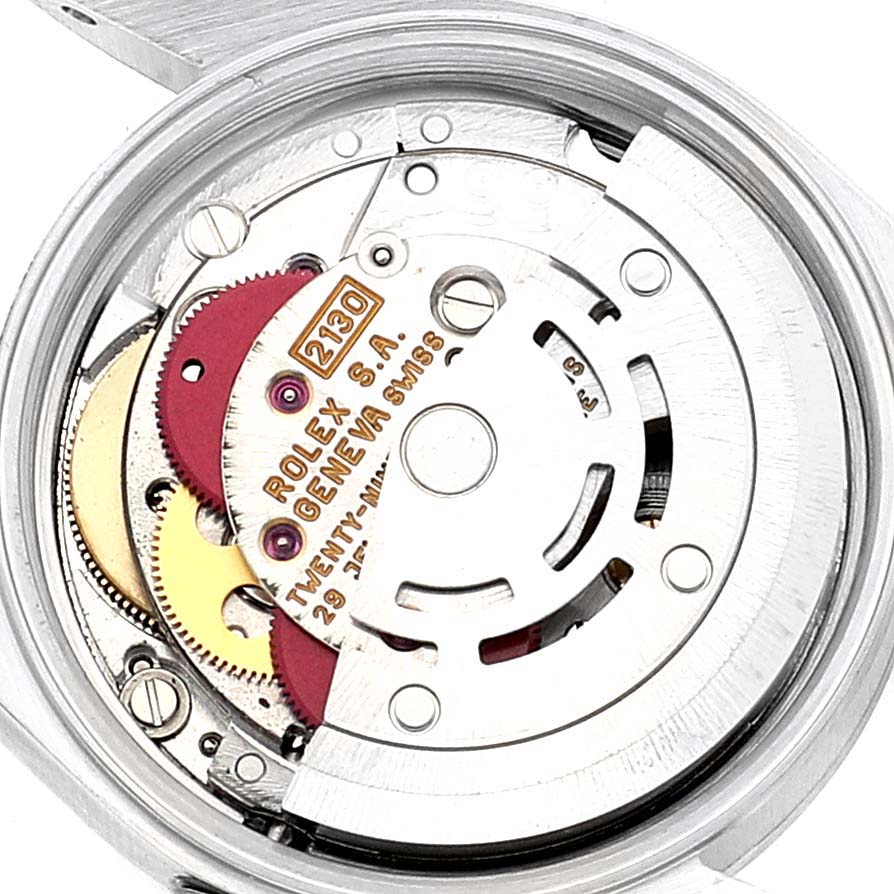 The image shows the movement mechanism of a Rolex Oyster Perpetual 67180 Women's Stainless Steel Blue Dial 67180 Women's Stainless Steel Blue Dial watch from the back angle, revealing gears and markings.
