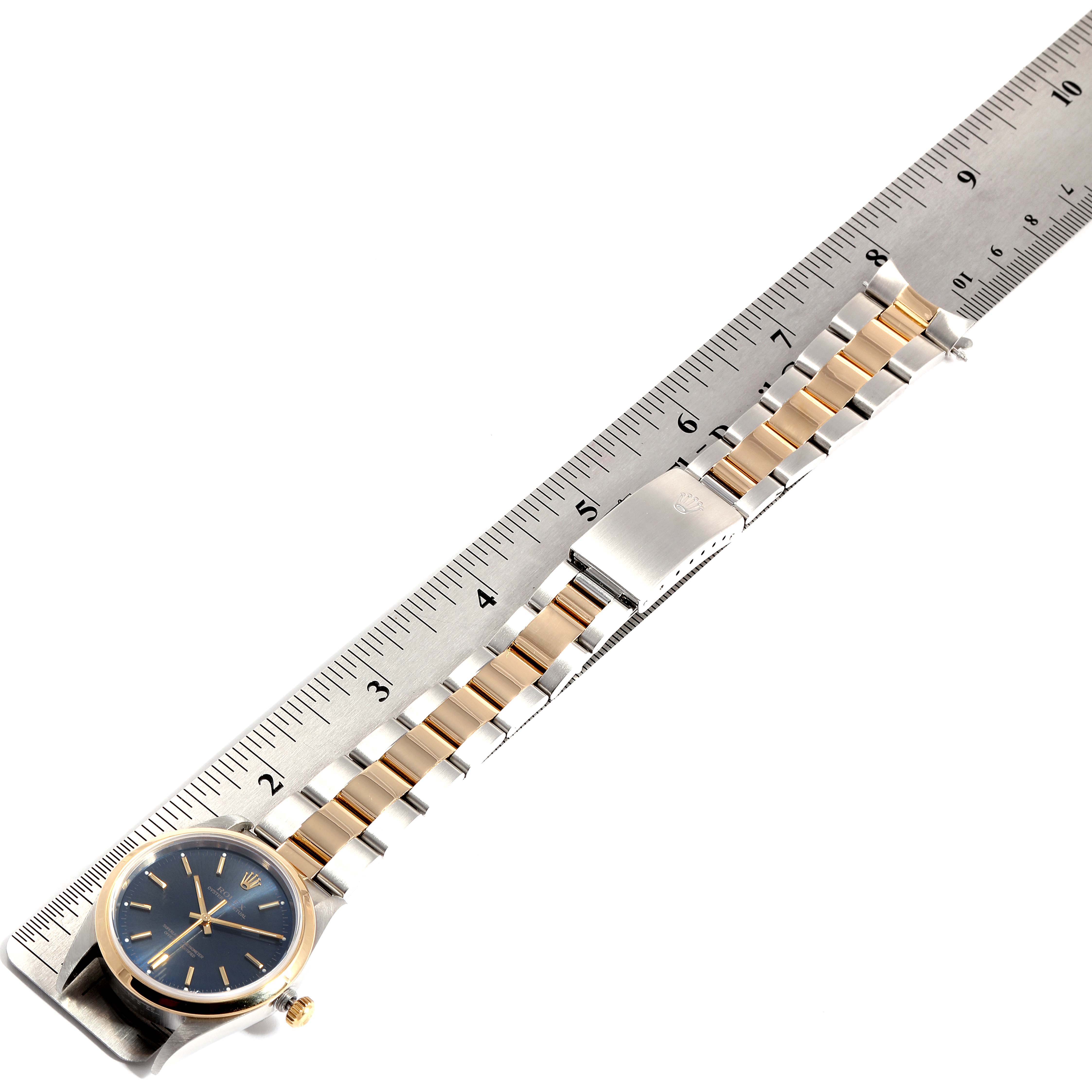 The image shows a Rolex Oyster Perpetual 14203 Men's Steel and Gold (two tone) Blue Dial 14203 Men's Steel and Gold (two tone) Blue Dial watch and its bracelet laid out next to a ruler for scale.