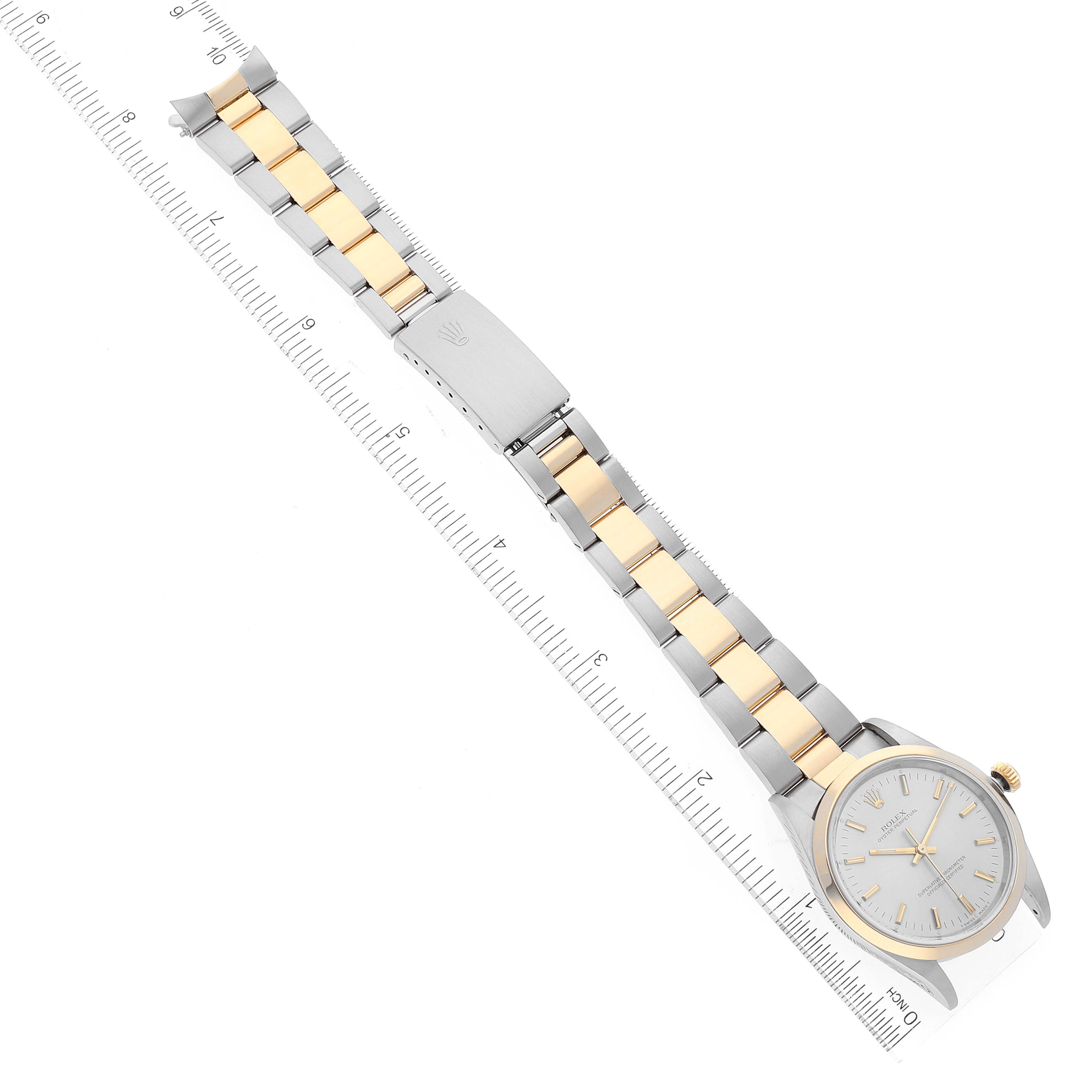 The image shows a Rolex Oyster Perpetual 14203 Men's Steel and Gold (two tone) Silver Dial 14203 Men's Steel and Gold (two tone) Silver Dial watch laid flat, highlighting its two-tone bracelet and clasp, alongside a measuring ruler.
