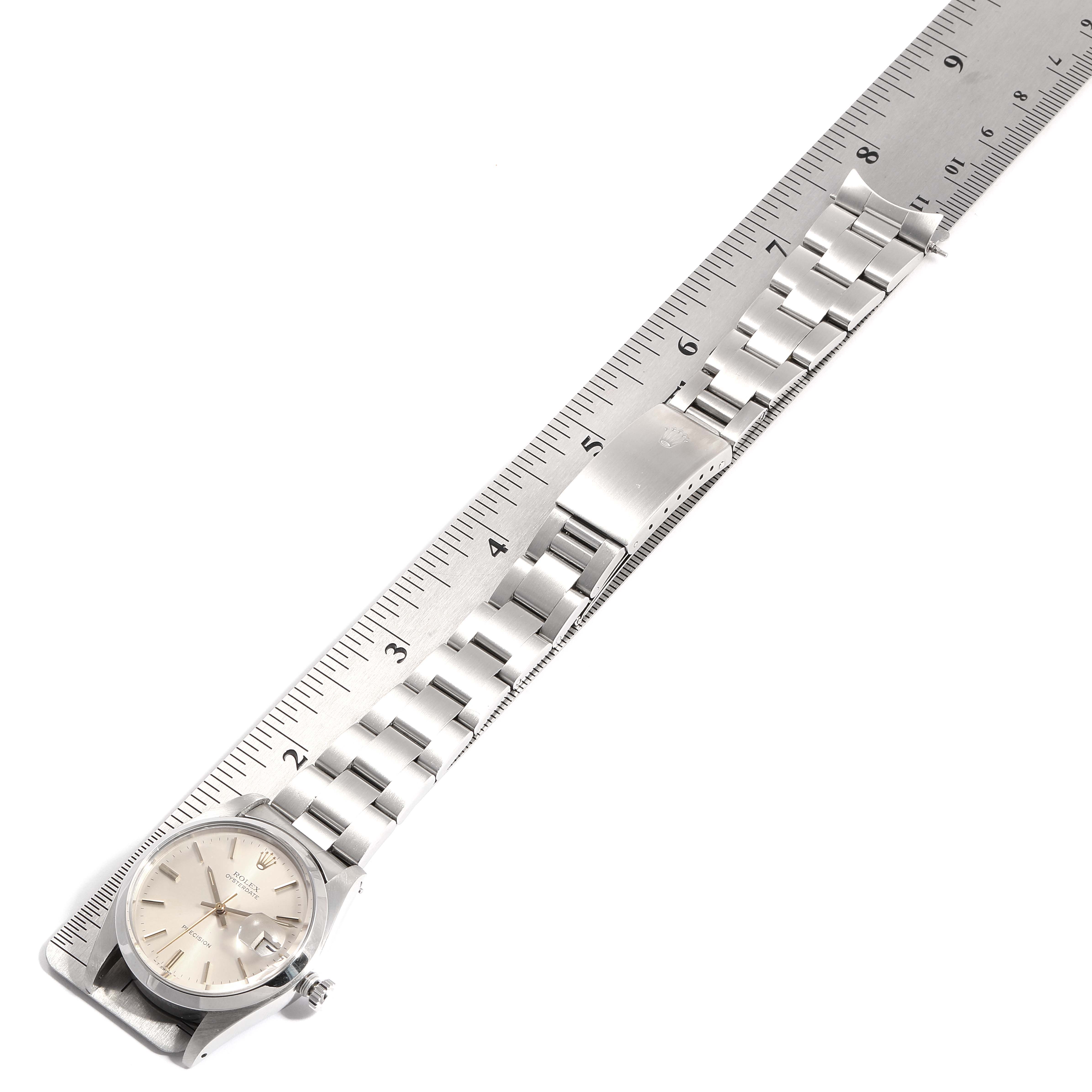 The image shows a Rolex Vintage Collection 6694 Men
s Stainless Steel Silver Dial 6694 Men
s Stainless Steel Silver Dial watch laid flat alongside a ruler, highlighting the face, bracelet, and clasp.