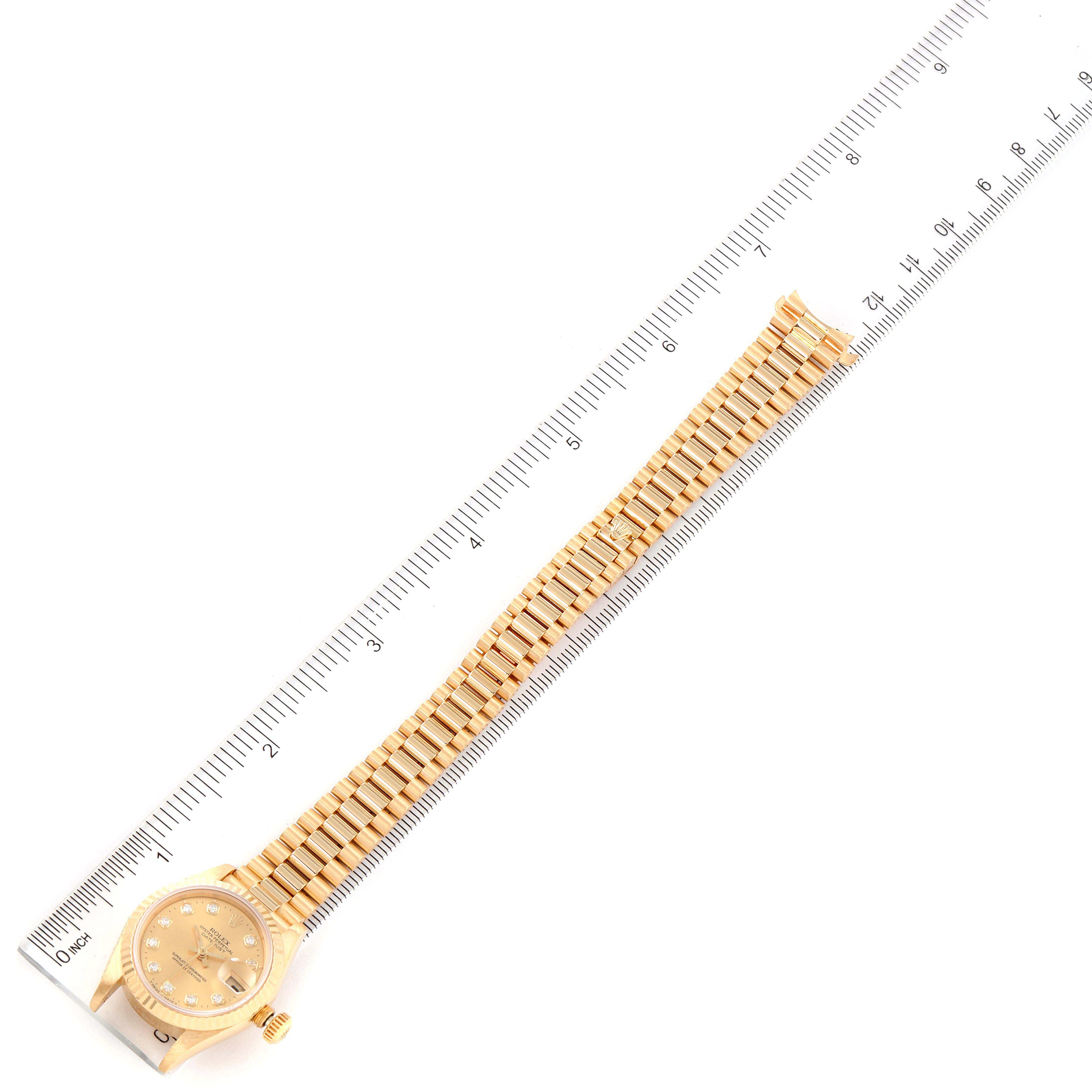 This image displays a Rolex President 69178 Women
s Yellow Gold Champagne Dial 69178 Women
s Yellow Gold Champagne Dial model watch laid flat alongside a ruler for measurement.