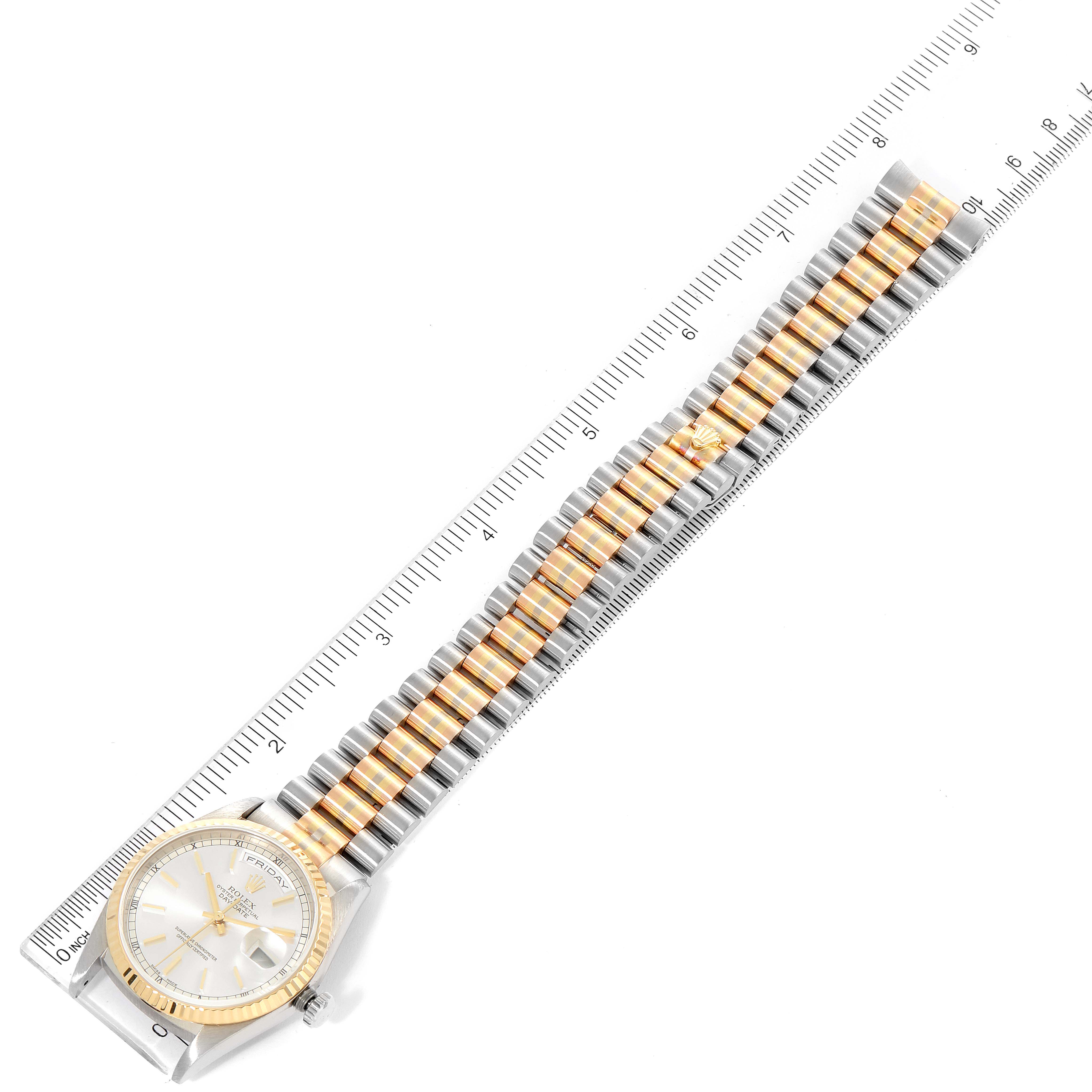 The image shows a Rolex President 18239 Men
s White Gold Silver Dial 18239 Men
s White Gold Silver Dial model watch laid flat with its gold and silver band extended, alongside a measuring ruler.