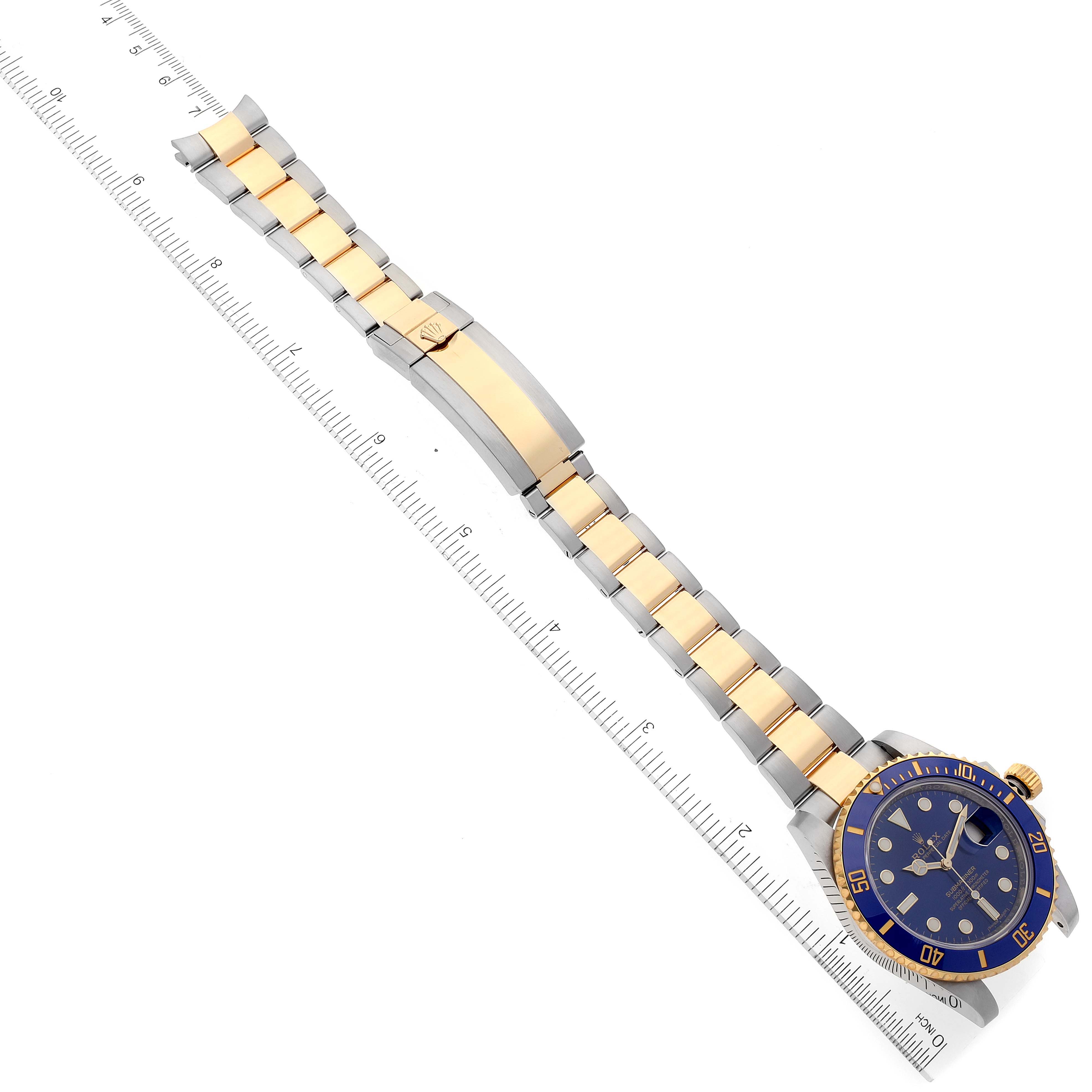 The image shows a Rolex Submariner 116613 Men
s Steel and Gold (two tone) Blue Dial 116613 Men
s Steel and Gold (two tone) Blue Dial watch laid flat, displaying the face, bezel, and bracelet with a ruler for scale.