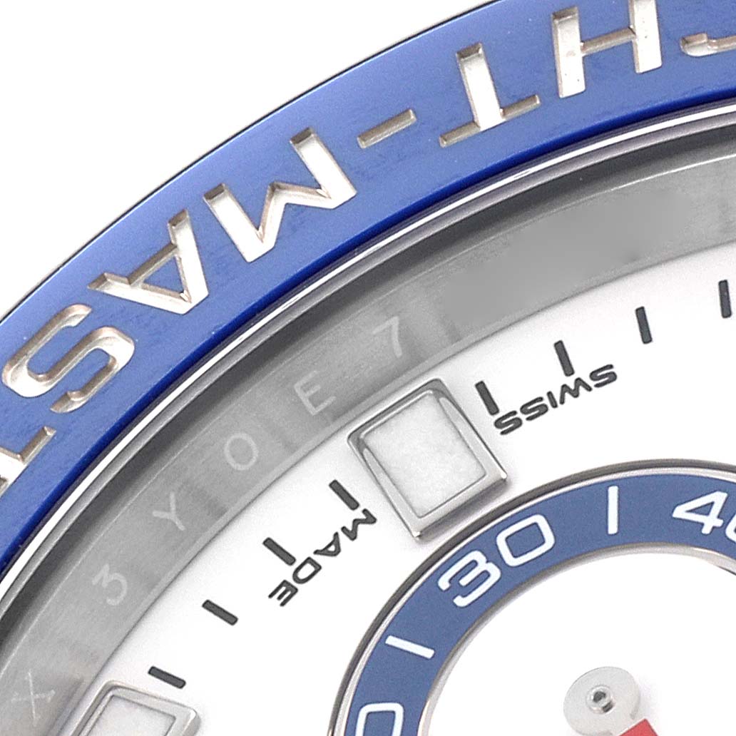 The image shows a close-up of the Rolex Yacht-Master 116680 Men's Stainless Steel White Dial watch, focusing on the blue bezel and part of the dial with indices.