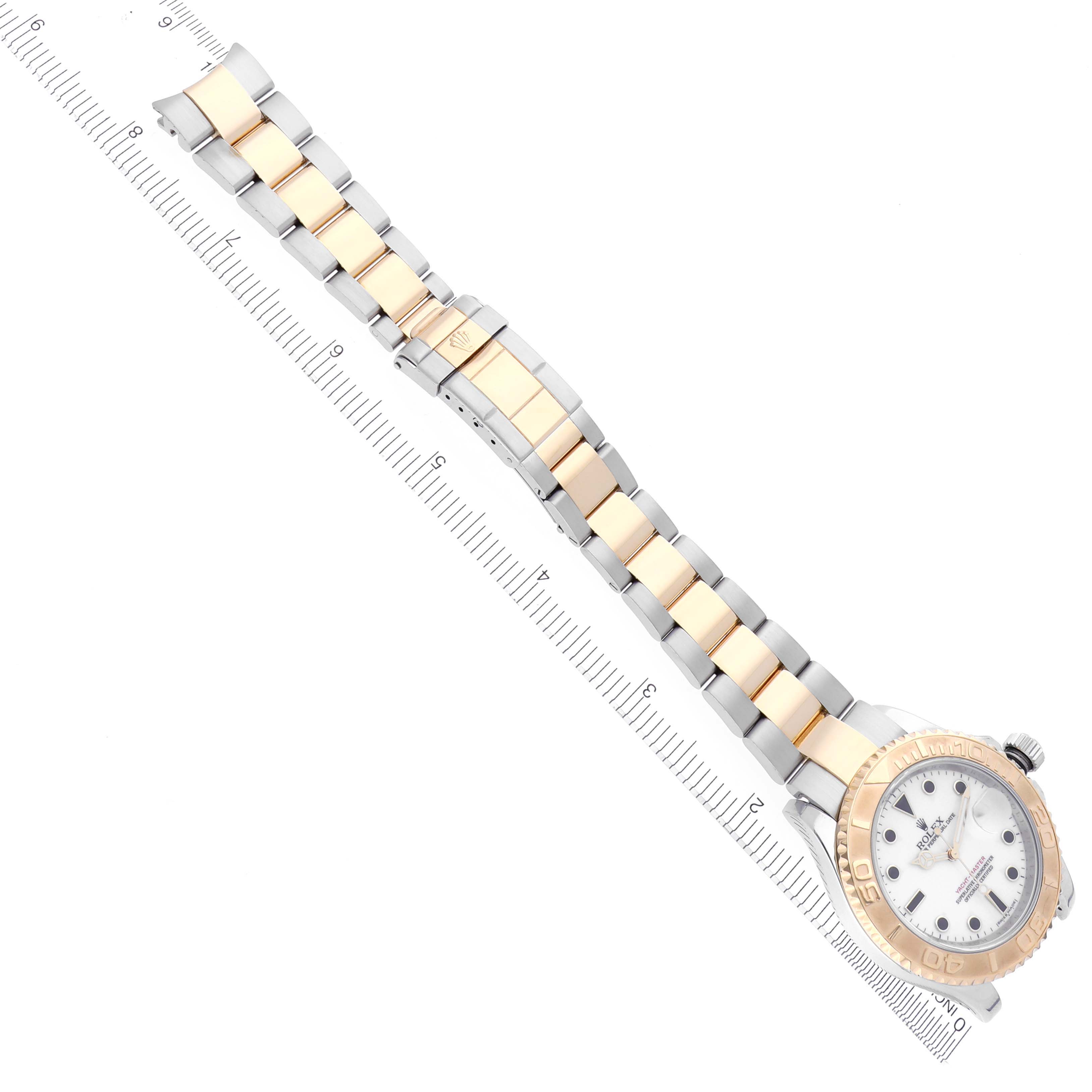 The Rolex Yacht-Master 16623 Men's Steel and Gold (two tone) White Dial watch is shown at a diagonal angle, displaying its full bracelet and case alongside a ruler for scale.