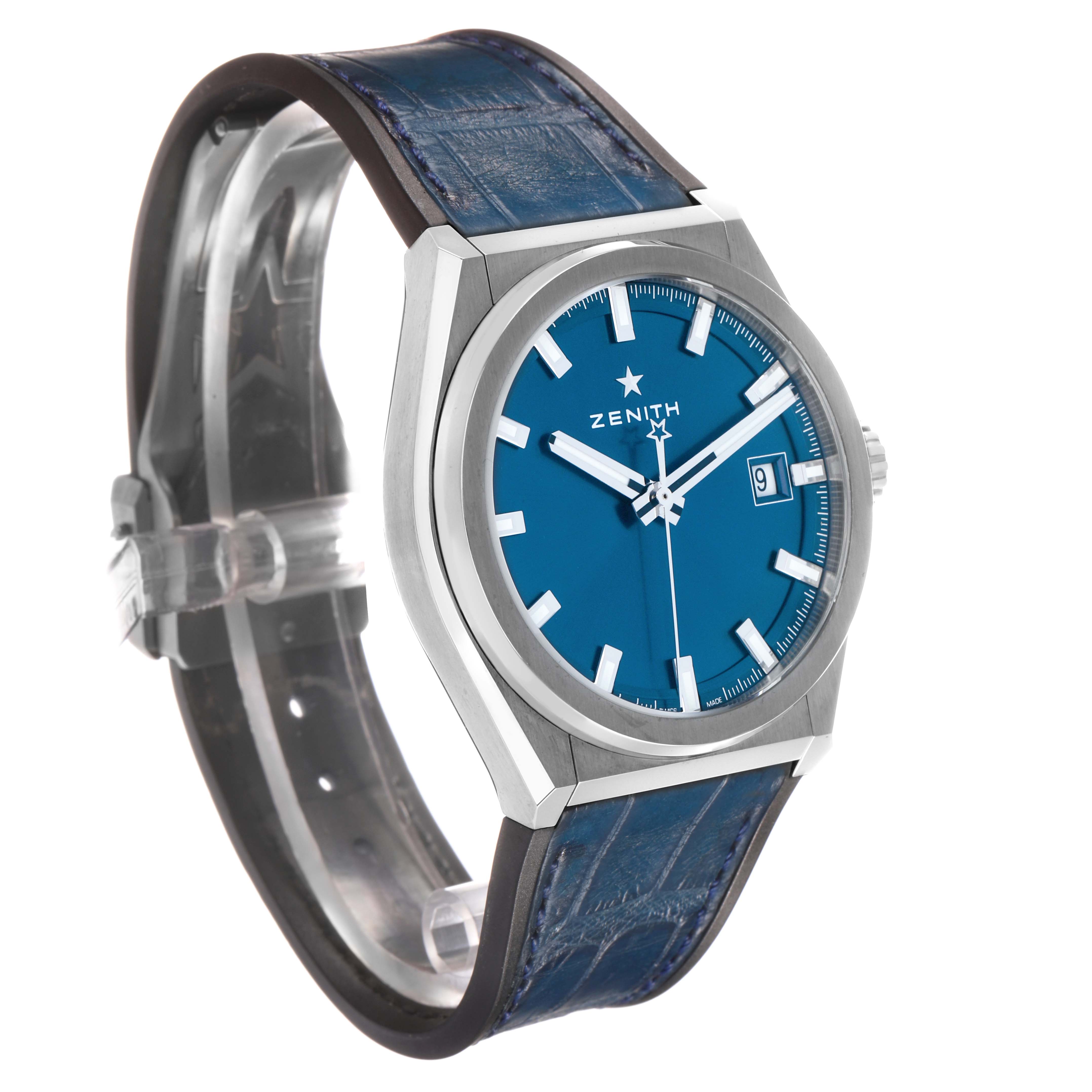 The Zenith Defy 95.9000.670/51.M9000 Men's Titanium Blue Dial watch is shown at an angled side view, displaying the dial, case, crown, and blue leather strap.