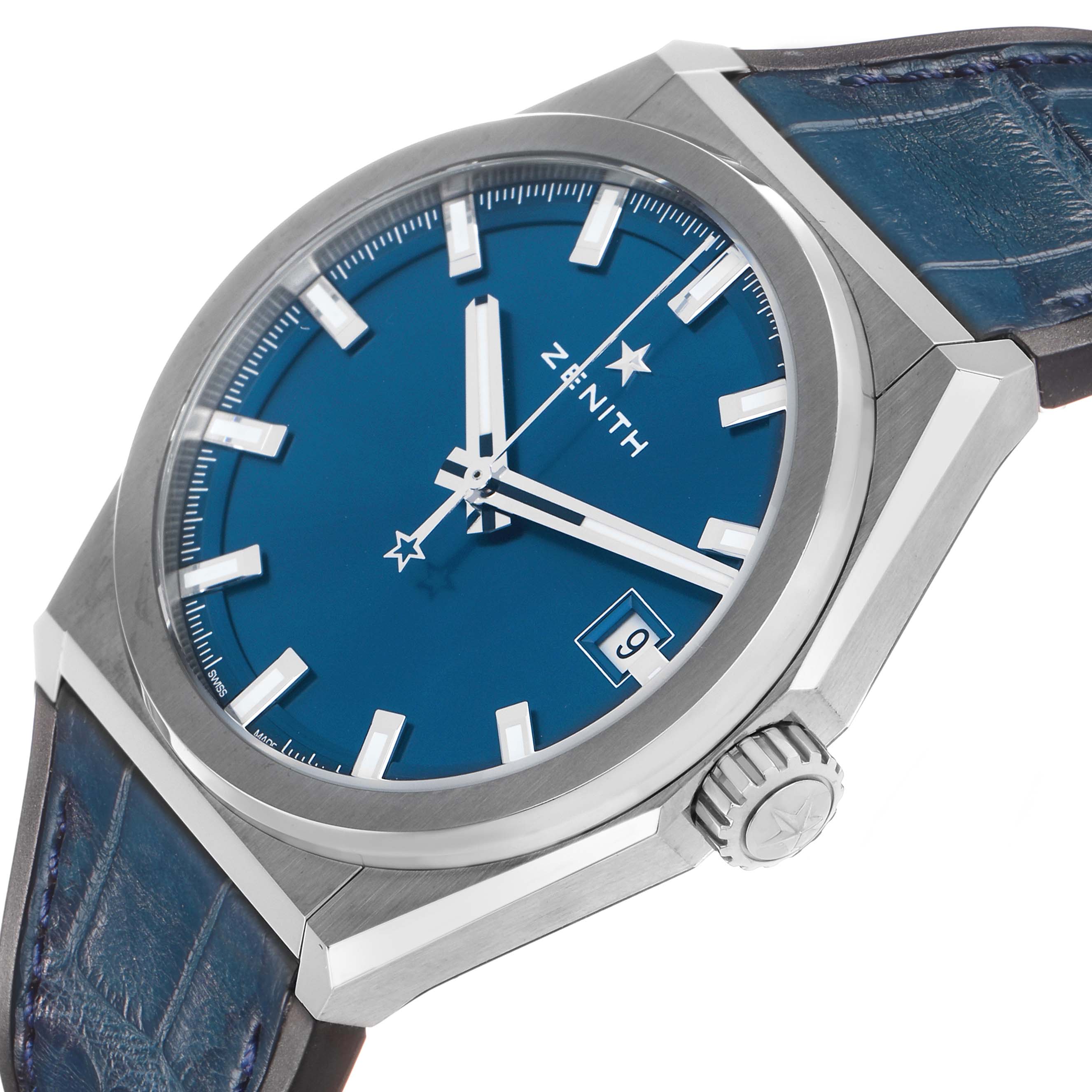 The Zenith Defy 95.9000.670/51.M9000 Men's Titanium Blue Dial watch is shown at an oblique angle, highlighting the blue dial, date window, crown, and leather strap.