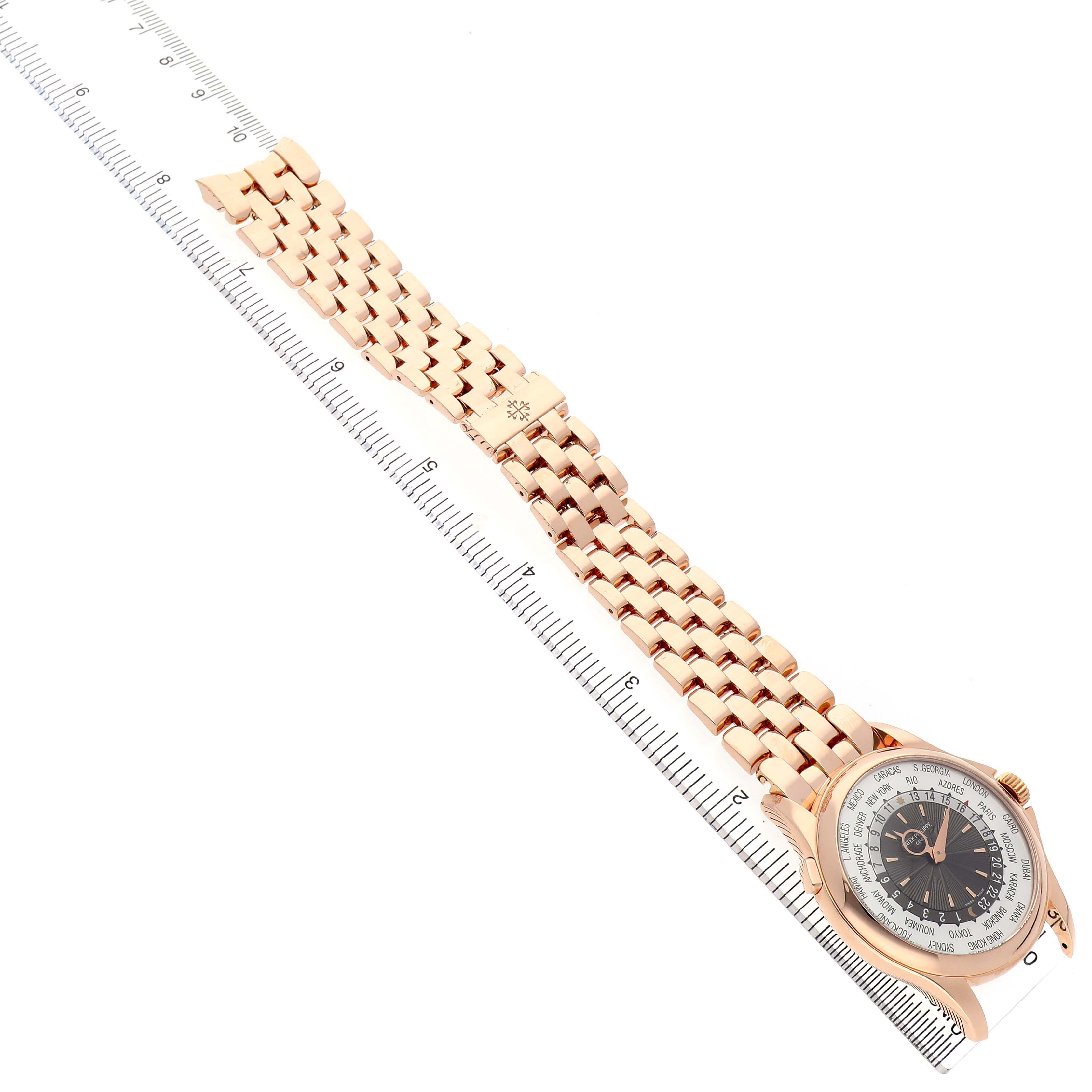 The Patek Philippe Complications 5130/1R-011 Men's Rose Gold Brown Dial watch is shown from an angled top view, highlighting the dial, case, and bracelet against a ruler.