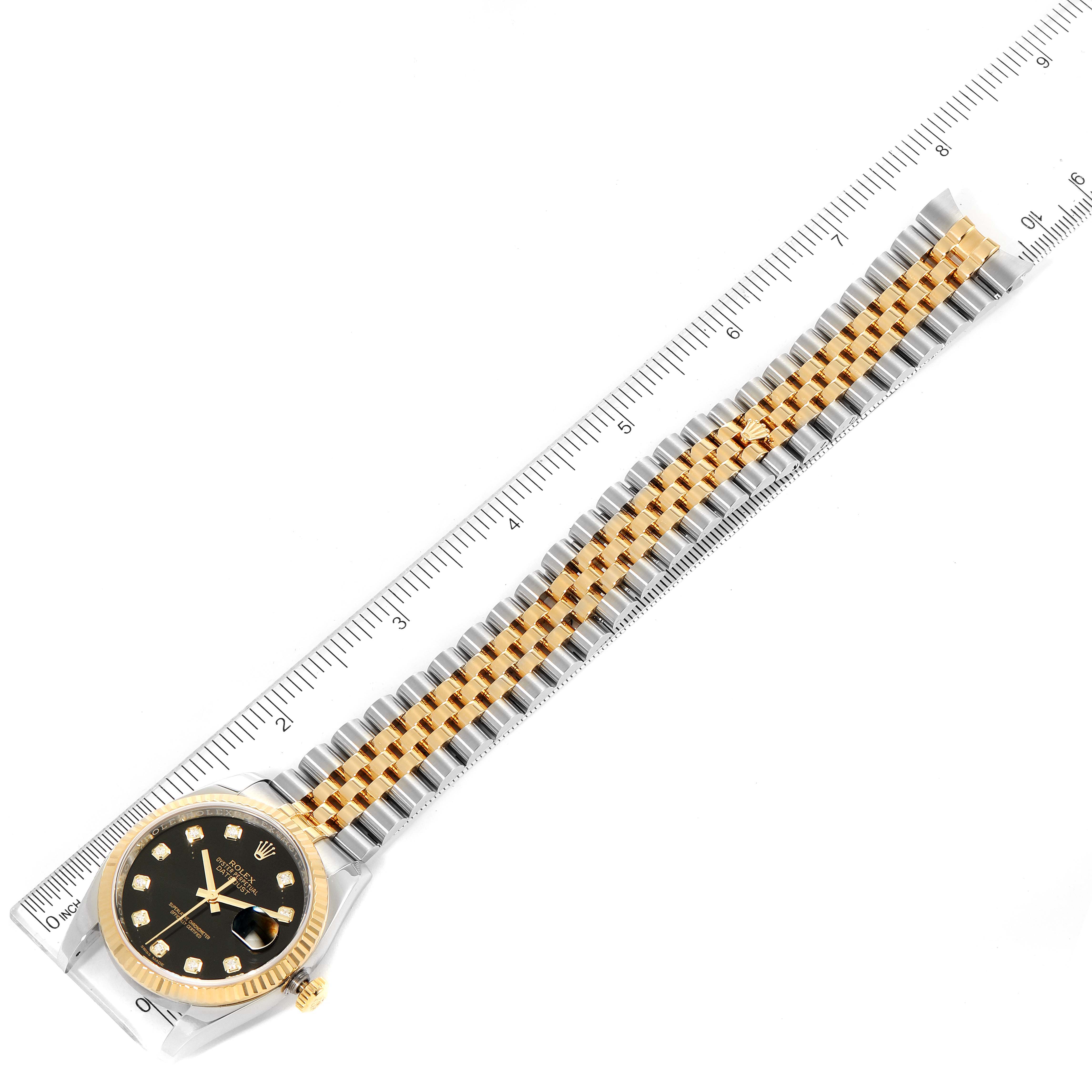 The image shows a top-down view of a Rolex Datejust 116233 Men
s Steel and Gold (two tone) Black Dial 116233 Men
s Steel and Gold (two tone) Black Dial watch, displaying its face, bracelet, and a ruler for scale.