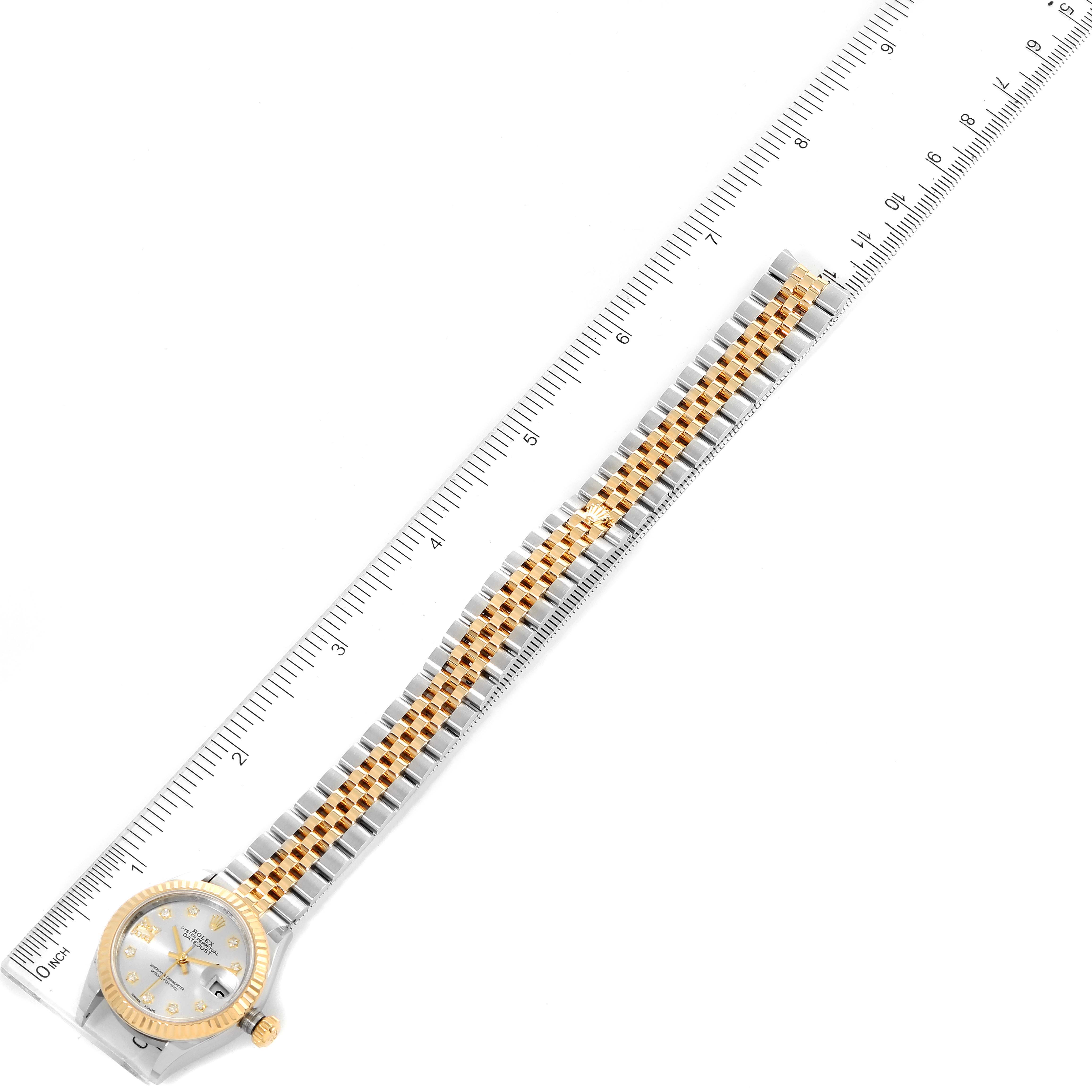 The image shows a top-down view of a Rolex Datejust 279173 Women
s Steel and Gold (two tone) Silver Dial 279173 Women
s Steel and Gold (two tone) Silver Dial watch with its gold and silver bracelet aligned next to a ruler.