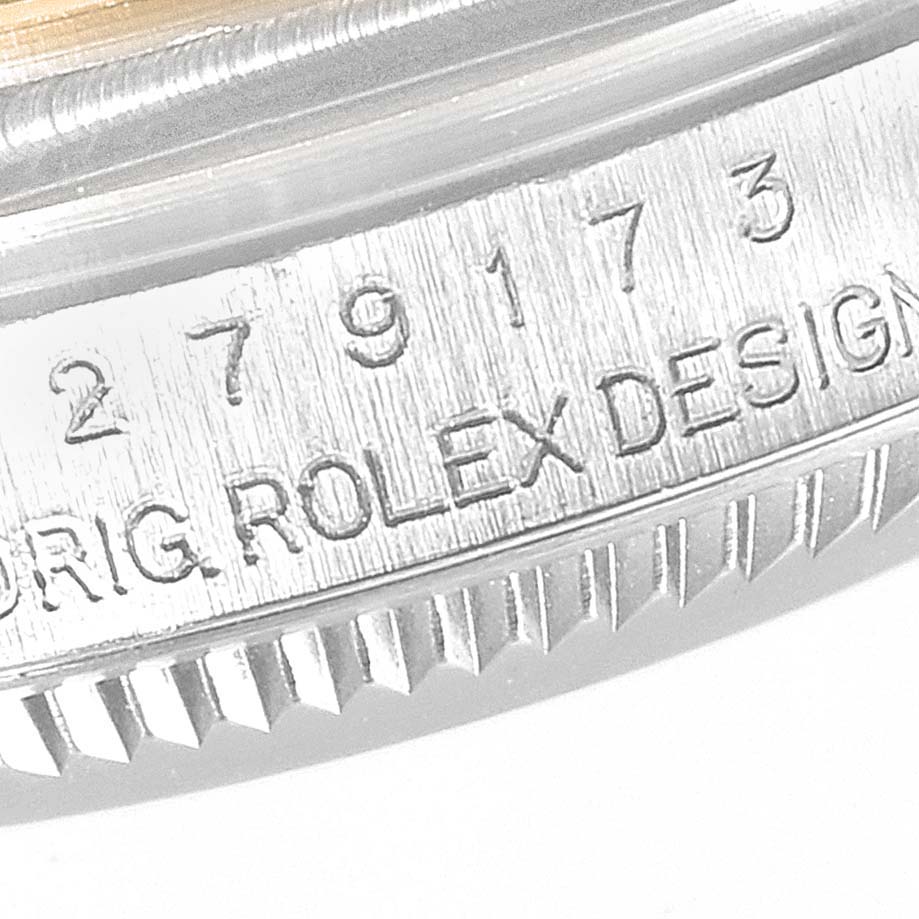 This image shows an angled close-up of the edge of a Rolex Datejust 279173 Women
s Steel and Gold (two tone) Silver Dial 279173 Women
s Steel and Gold (two tone) Silver Dial model, highlighting the serial number and "ROLEX DESIGN" engraving.