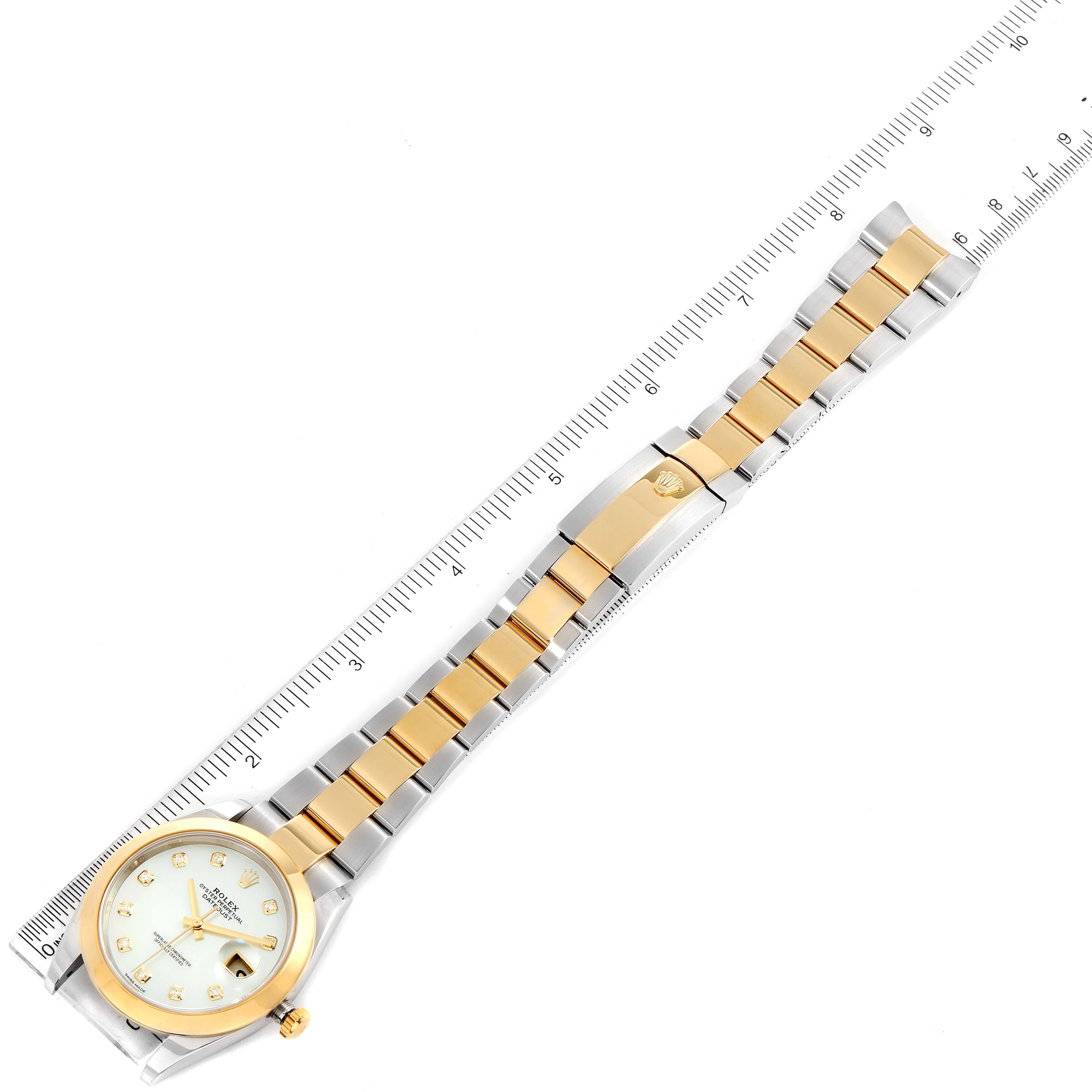 The image shows a top view of a Rolex Datejust 41 126303 Men
s Steel and Gold (two tone) Mother of Pearl Dial 126303 Men
s Steel and Gold (two tone) Mother of Pearl Dial watch with its full bracelet extended along a ruler.