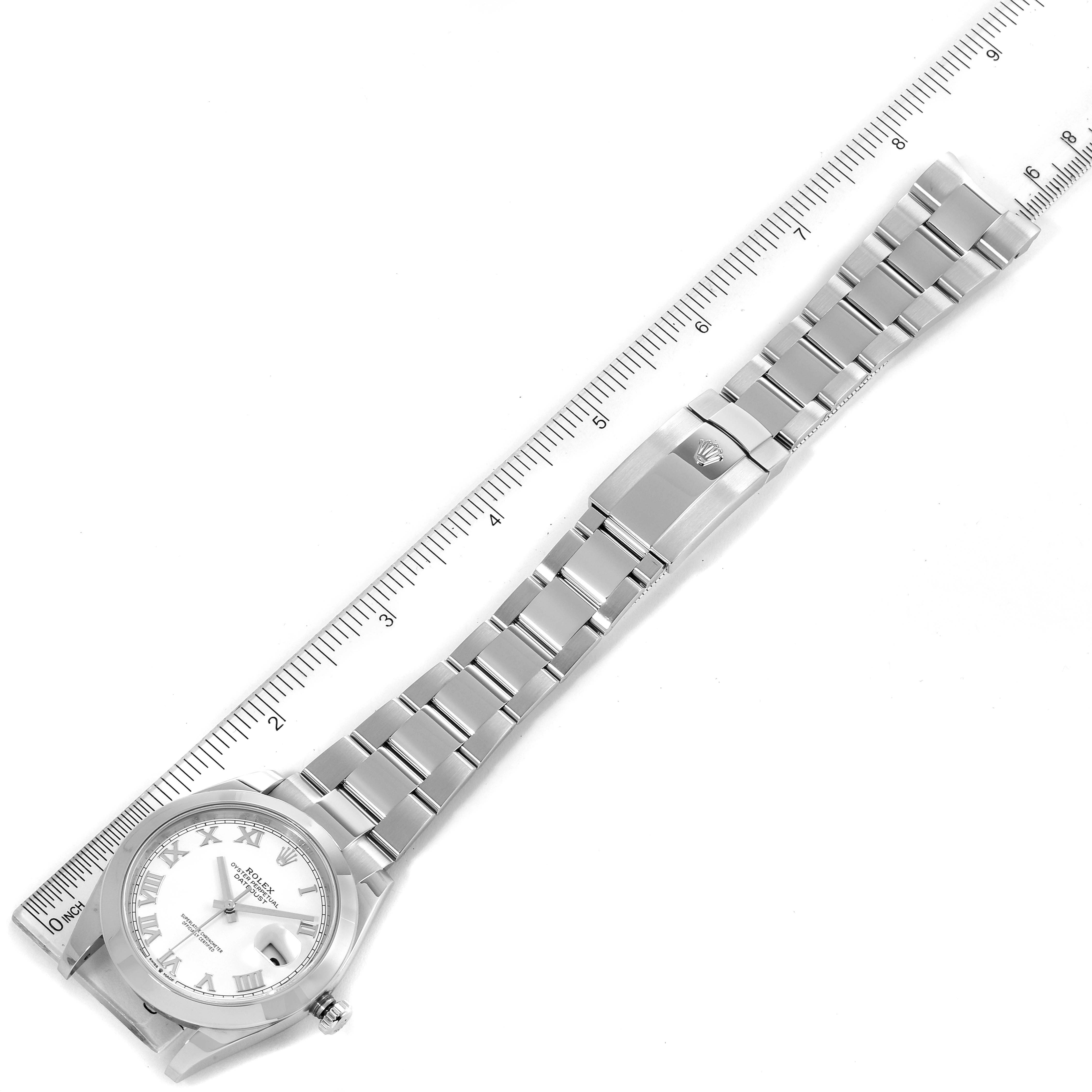 The image shows a top view of a Rolex Datejust 41 126300 Men's Stainless Steel White Dial 126300 Men's Stainless Steel White Dial watch with its bezel, dial, bracelet, and clasp next to a measuring ruler.