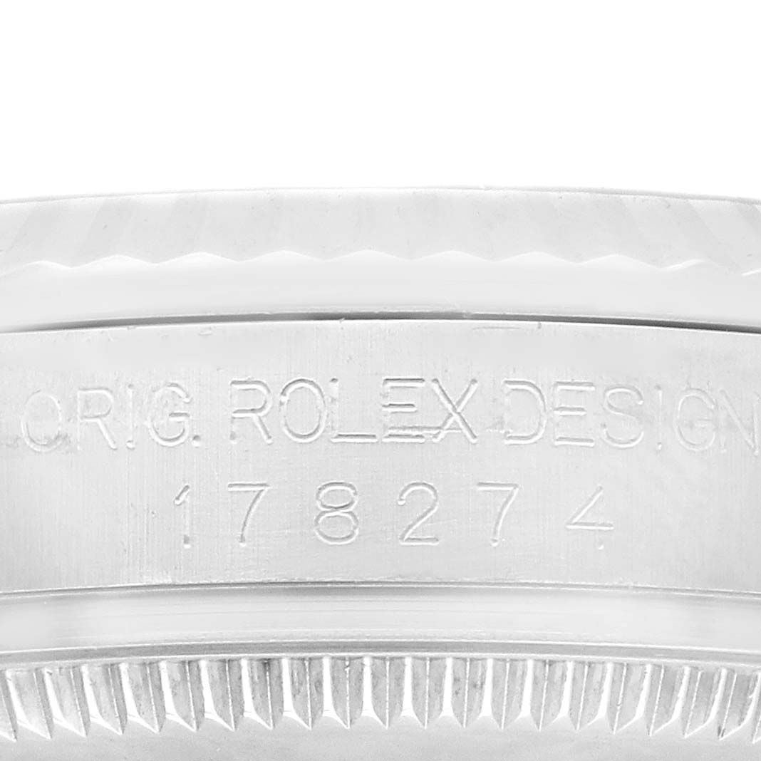This image shows the engraved serial number and part of the bezel of a Mid-Size Rolex watch.