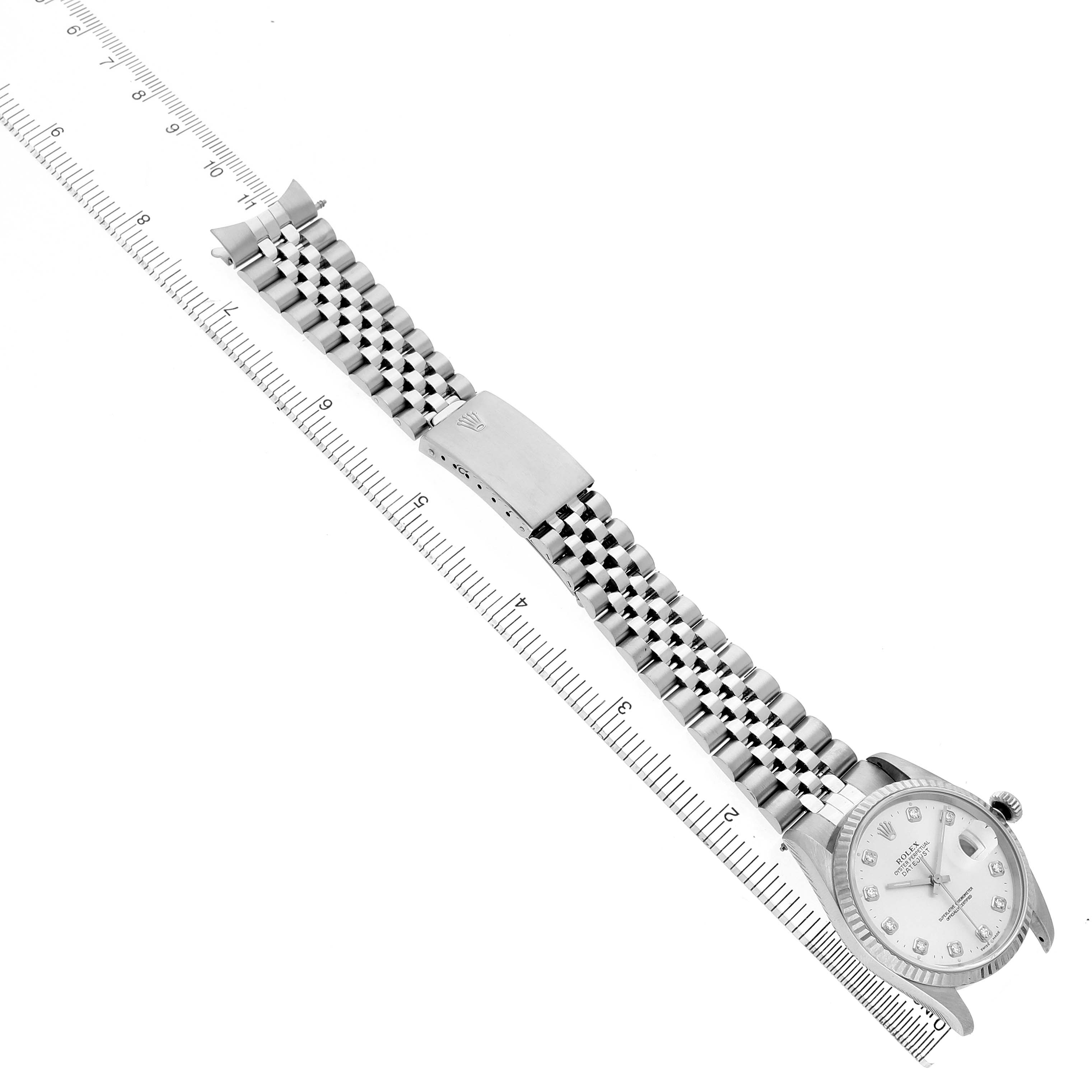 The Rolex Datejust 16234 Men's Stainless Steel Silver Dial watch is shown from an overhead angle, featuring its face, bracelet, and clasp alongside a ruler for scale.