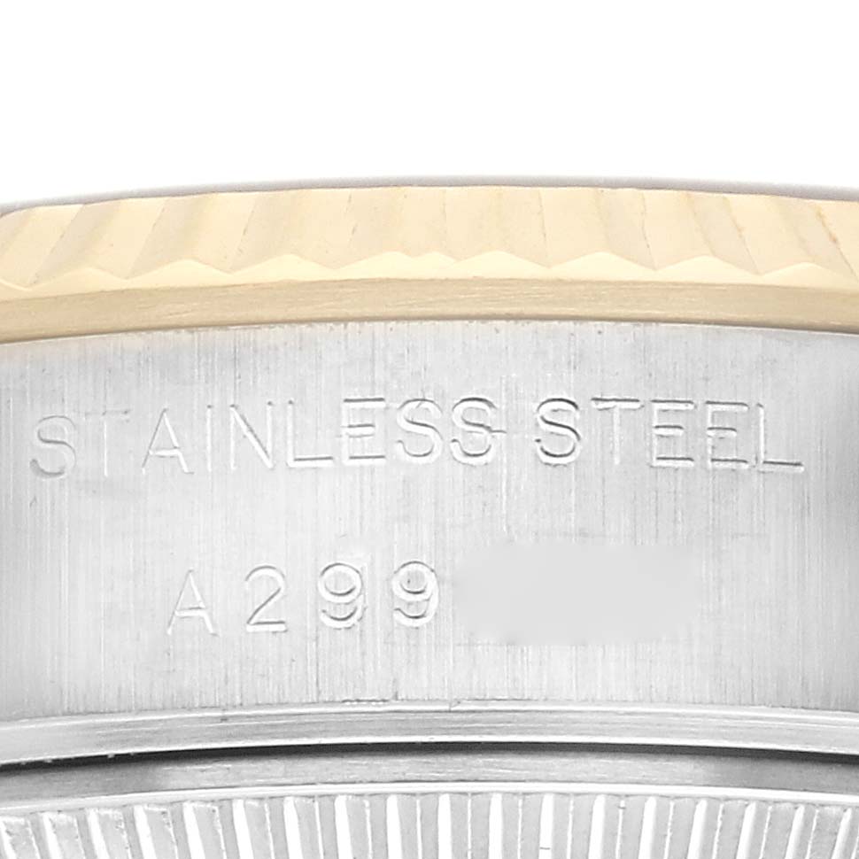 The image shows a close-up of a Rolex Datejust 79173 Women
s Steel and Gold (two tone) Champagne Dial 79173 Women
s Steel and Gold (two tone) Champagne Dial watch
s bezel and engraved stainless steel part from a side angle.