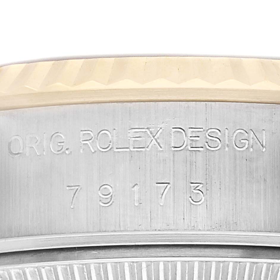 The image shows a close-up of the side of a Rolex Datejust 79173 Women
s Steel and Gold (two tone) Champagne Dial 79173 Women
s Steel and Gold (two tone) Champagne Dial, highlighting the engraved design number and bezel edge.