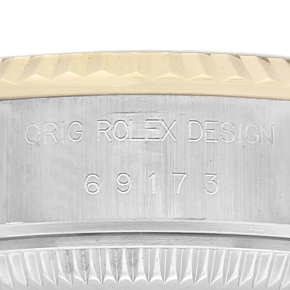 The image shows a close-up of a Rolex Datejust 69173 Women
s Steel and Gold (two tone) Champagne Dial 69173 Women
s Steel and Gold (two tone) Champagne Dial model, highlighting its bezel with engraved model number 69173 and "ORIG ROLEX DESIGN."