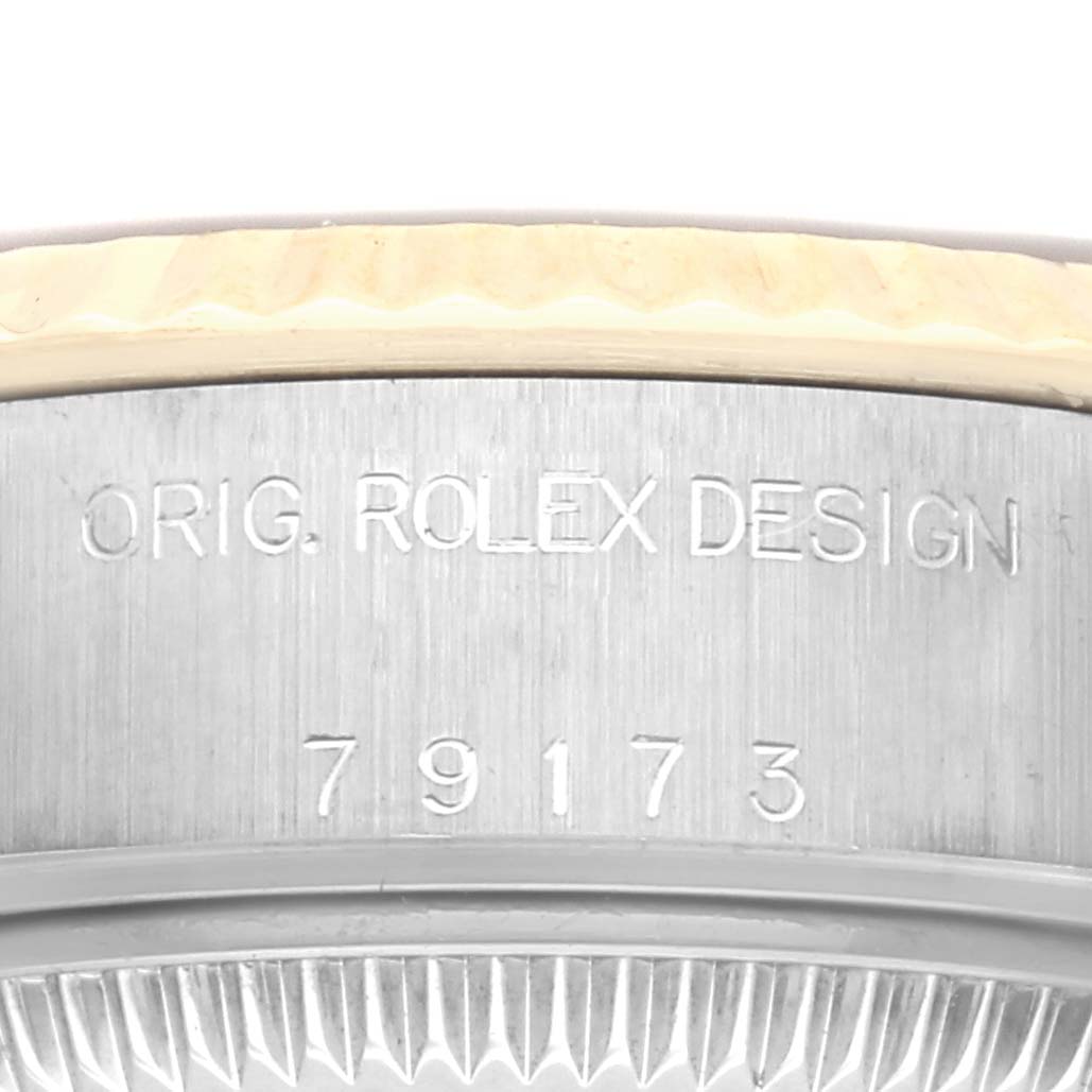 The image shows the side view of a Rolex Datejust 79173 Women
s Steel and Gold (two tone) Black Dial 79173 Women
s Steel and Gold (two tone) Black Dial case with the engraving "ORIG. ROLEX DESIGN 79173".