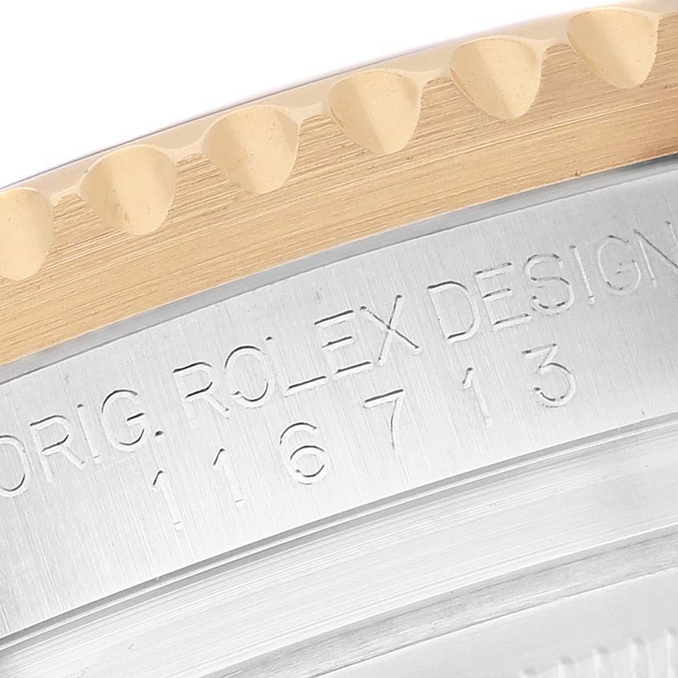 The image shows a close-up of the bezel and engraving on a Rolex GMT-Master M116713LN Men's Stainless Steel Black Dial watch, detailing its brushed metal surface.