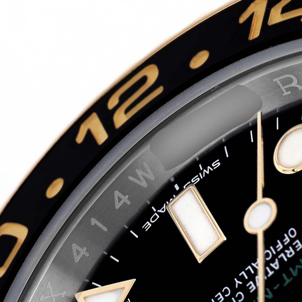 The image shows a close-up of a Rolex GMT-Master M116713LN Men's Stainless Steel Black Dial watch bezel and part of the dial, highlighting the 12 marker.