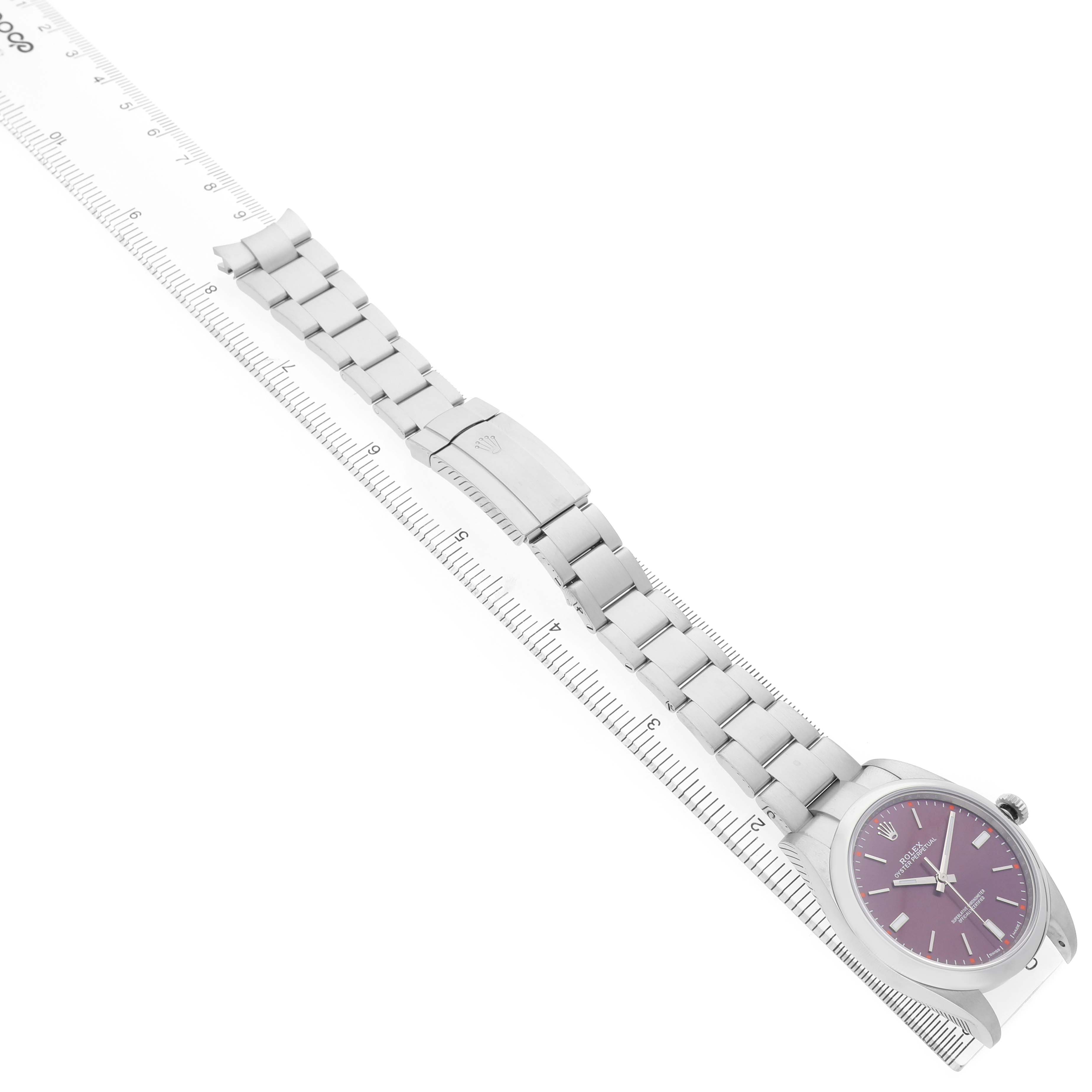 The Rolex Oyster Perpetual 114300 Men's Stainless Steel Purple Dial watch is shown from a top view, highlighting the face, bracelet, and clasp alongside a ruler.