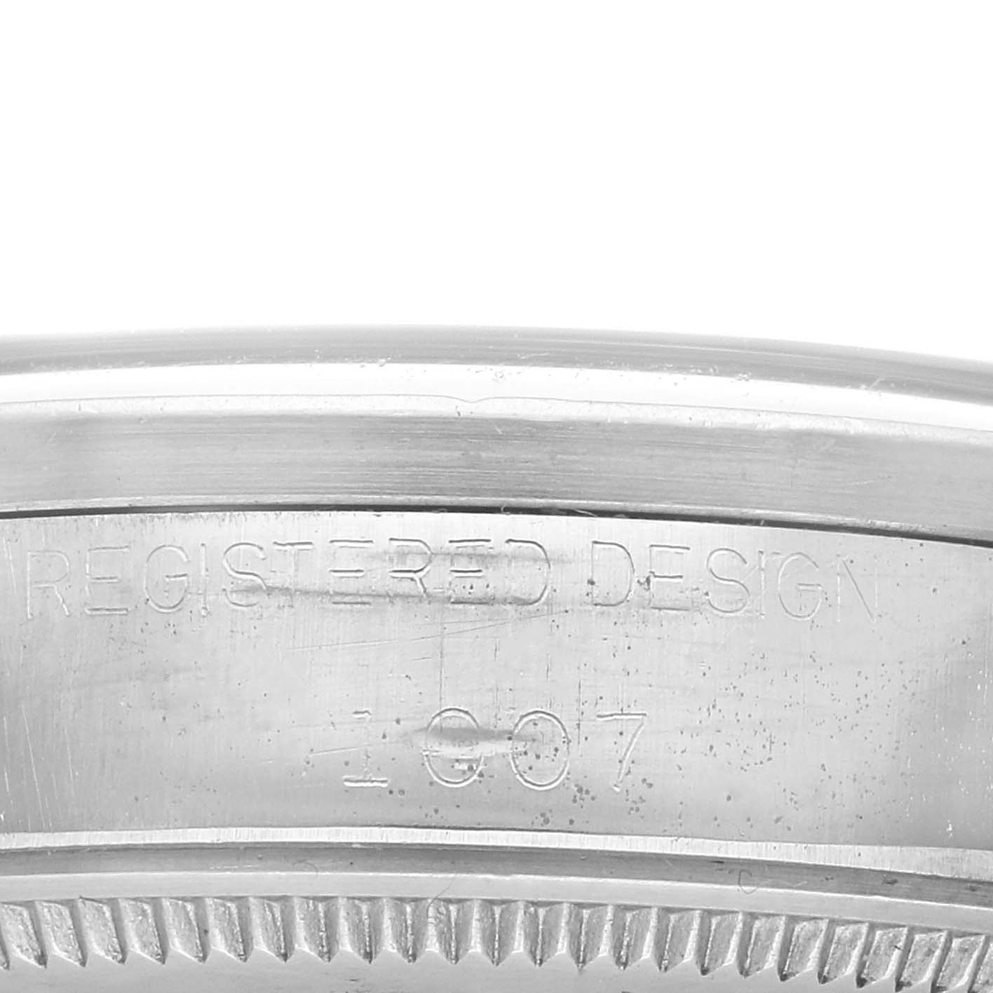 The image shows a close-up of the case side of a Rolex Oyster Perpetual 1007 Men
s Stainless Steel Silver Dial 1007 Men
s Stainless Steel Silver Dial, highlighting the "Registered Design" engraving.