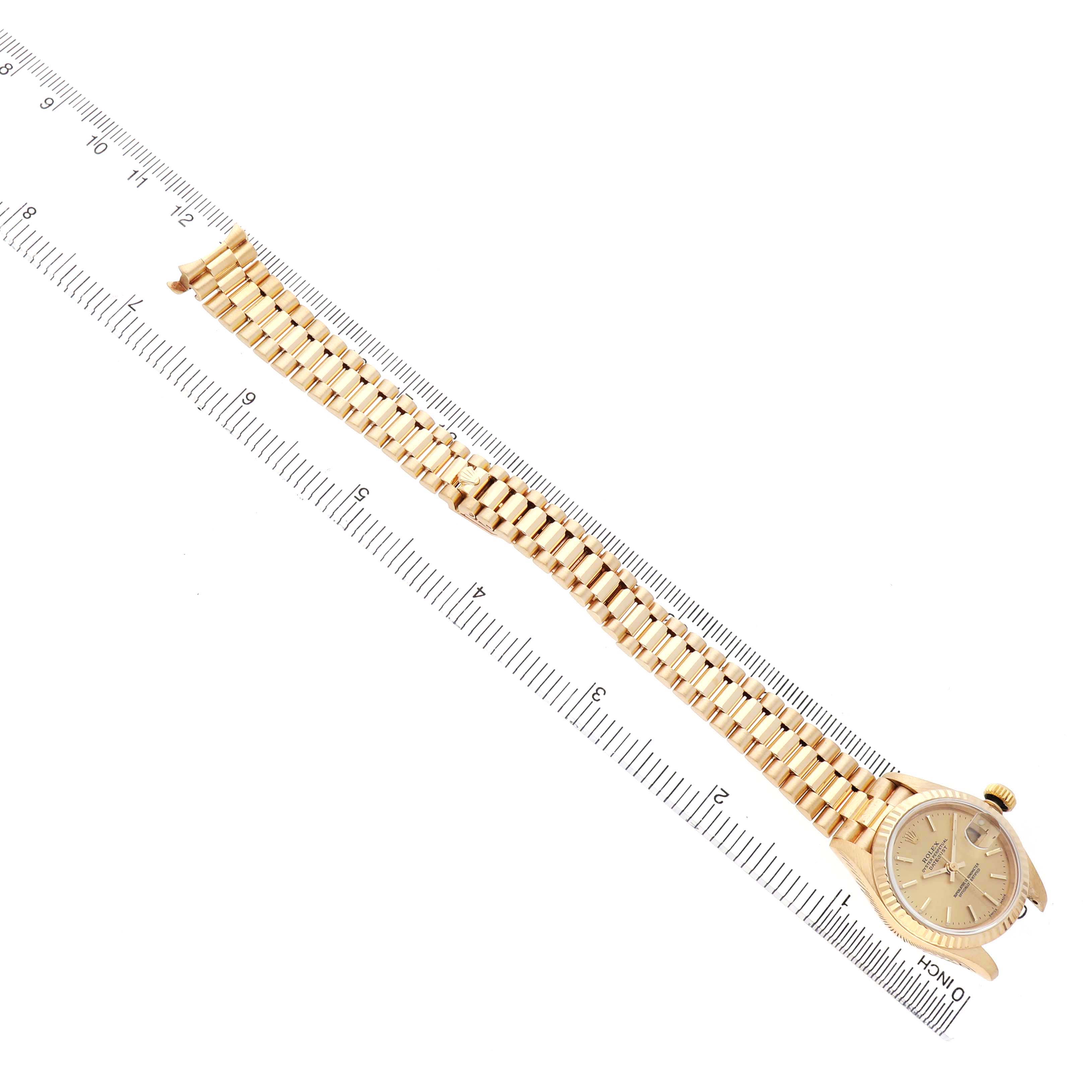 The Rolex President 69178 Women's Yellow Gold Champagne Dial watch is shown from an overhead angle, displaying the full bracelet and face alongside a ruler for scale.