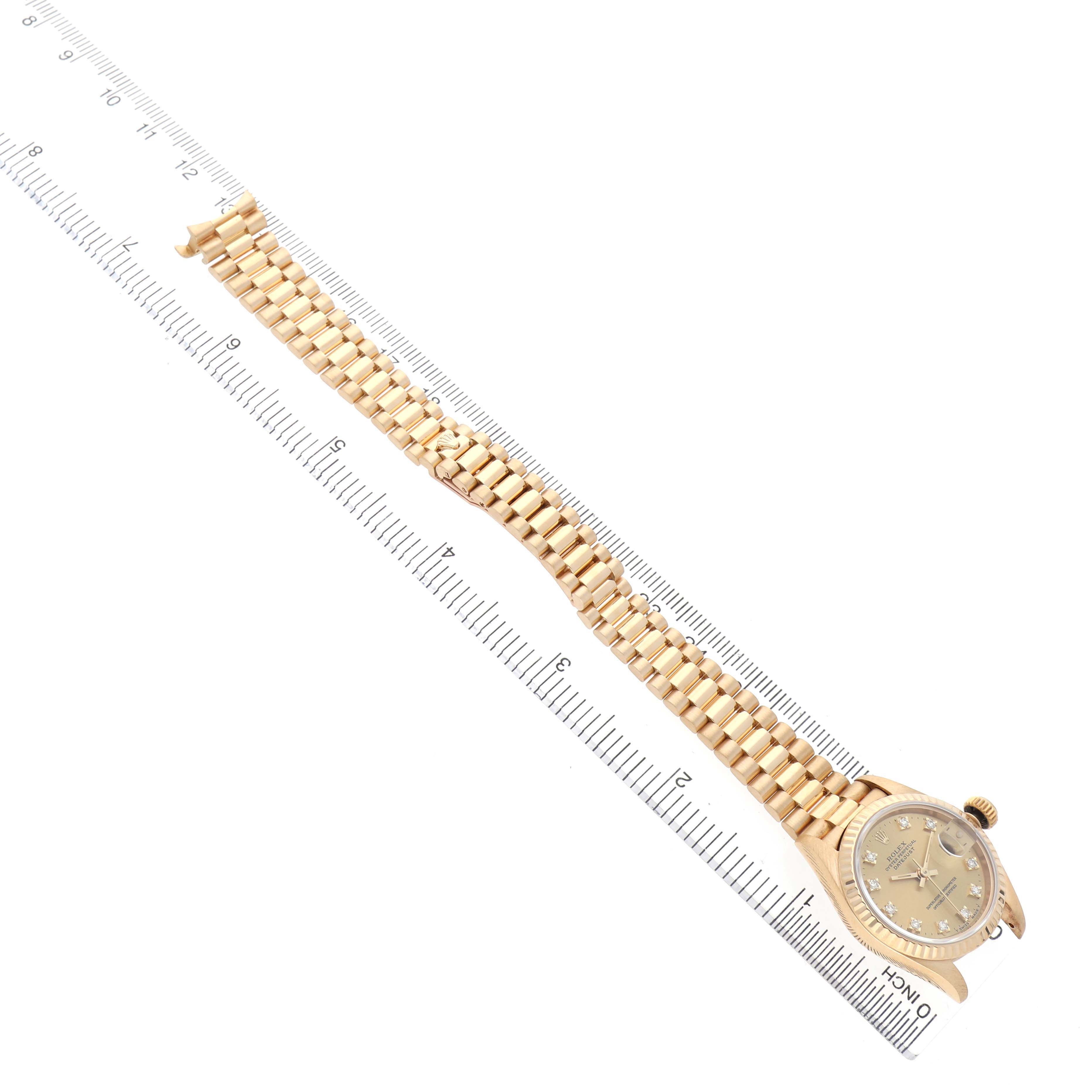 The Rolex President 69178 Women's Yellow Gold Champagne Dial watch is shown at an angle displaying the full bracelet and dial, placed alongside a ruler for scale.