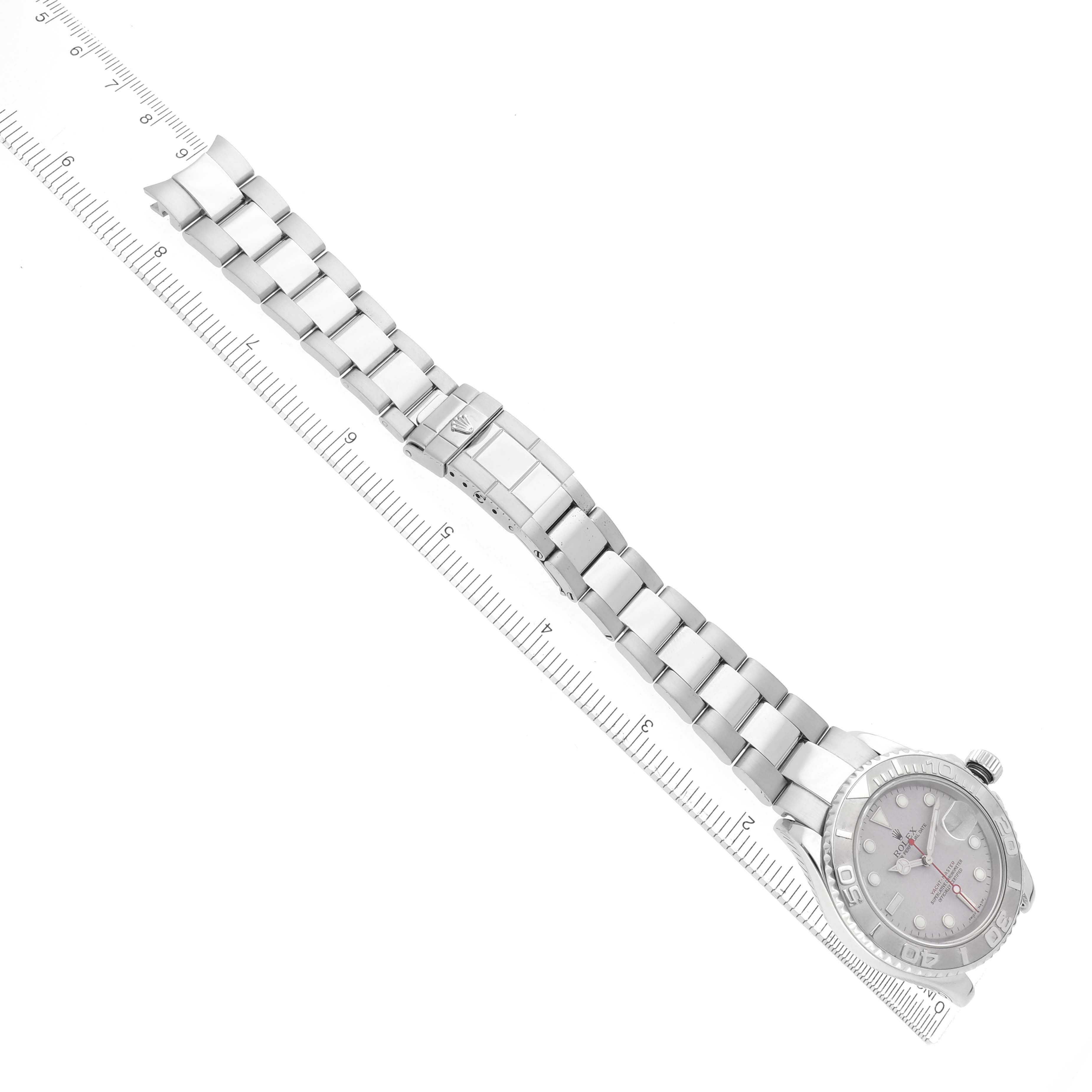 The Rolex Yacht-Master 16622 Men
s Stainless Steel Silver Dial 16622 Men
s Stainless Steel Silver Dial watch is shown from an overhead angle, displaying the bracelet, clasp, and case with a ruler for scale.
