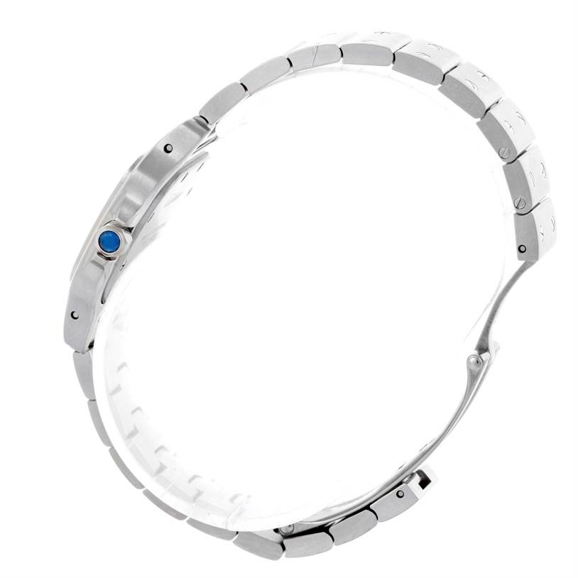 This Cartier Santos W20056D6 Women
s Stainless Steel Silver Dial W20056D6 Women
s Stainless Steel Silver Dial watch is viewed from a side angle, focusing on the bracelet and the crown with a blue gemstone.