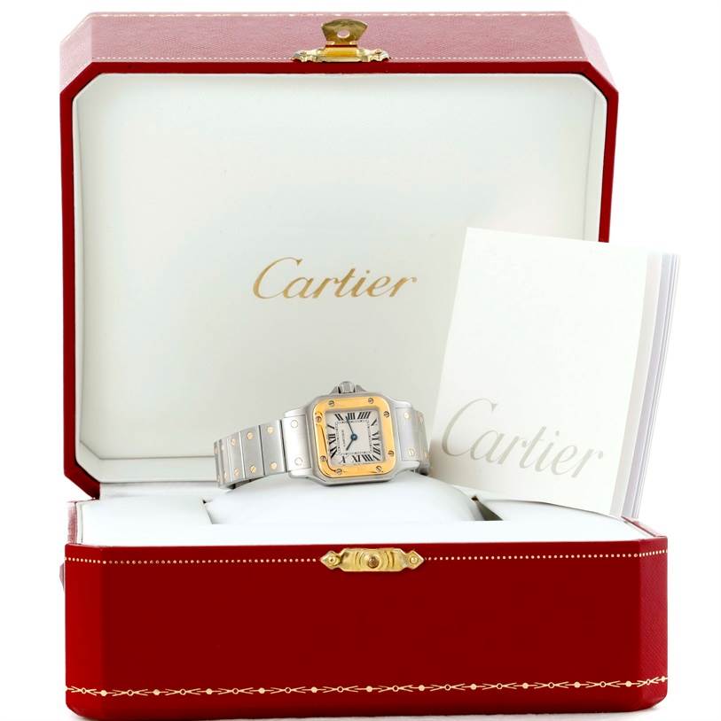 The Cartier Santos W20012C4 Women
s Stainless Steel Silver Dial W20012C4 Women
s Stainless Steel Silver Dial watch
s front view is displayed inside its red and gold box, accompanied by a booklet.