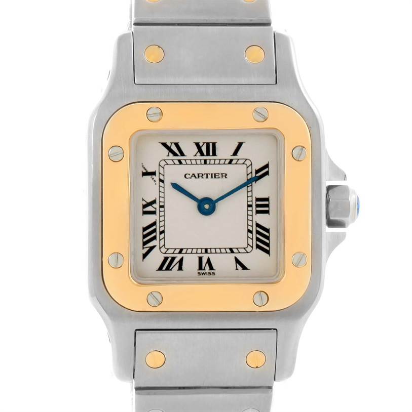 The image shows a Cartier Santos W20012C4 Women
s Stainless Steel Silver Dial W20012C4 Women
s Stainless Steel Silver Dial watch with a gold bezel, Roman numerals, blue hands, and part of its metal bracelet.