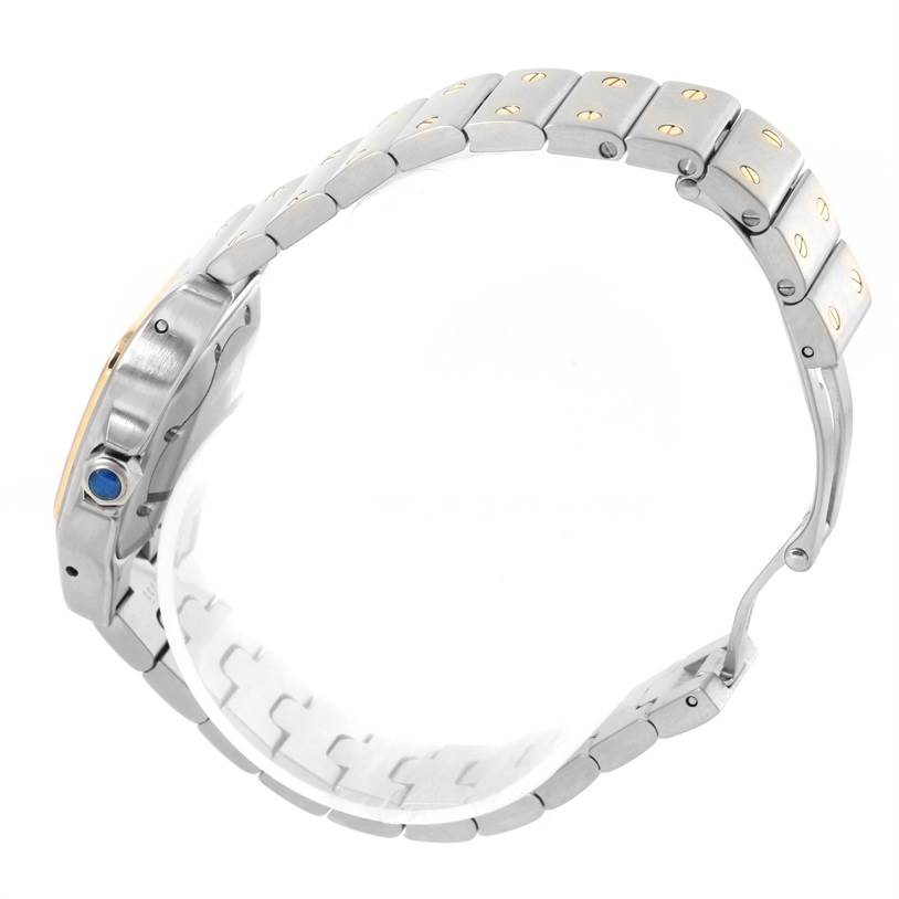 The image shows a side view of a Cartier Santos W20057C4 Women
s Stainless Steel Silver Dial W20057C4 Women
s Stainless Steel Silver Dial watch, featuring its metal bracelet and the winding crown with a blue gemstone.