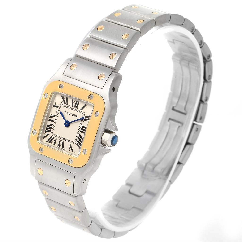 The image shows a Cartier Santos W20012C4 Women's Stainless Steel Silver Dial W20012C4 Women's Stainless Steel Silver Dial watch at a three-quarter angle, displaying its face, bezel, bracelet, and crown with a blue stone.