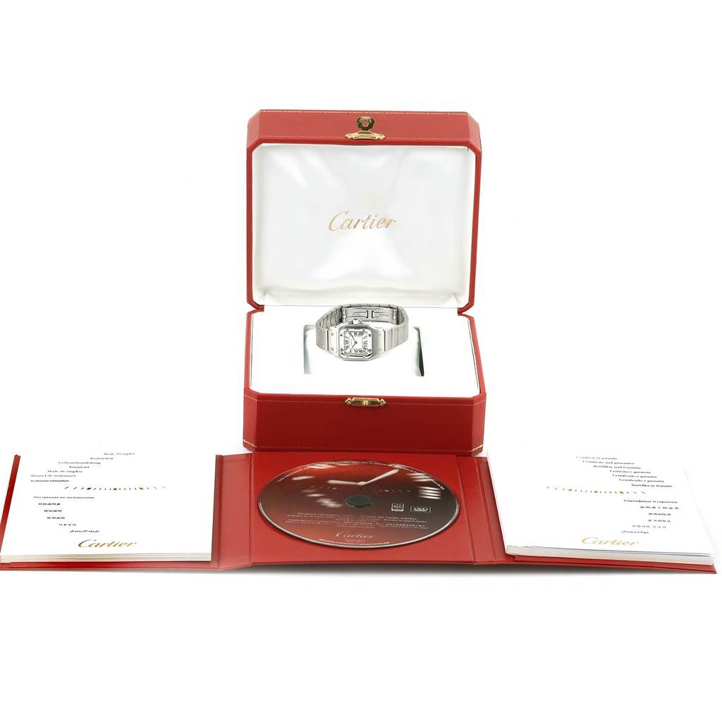The image shows a Cartier Santos W20056D6 Women
s Stainless Steel Silver Dial W20056D6 Women
s Stainless Steel Silver Dial watch in its red box, along with accompanying documents and a CD.