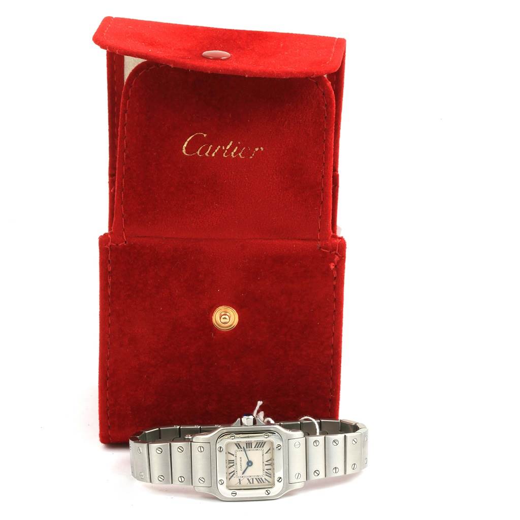 The image shows a Cartier Santos W20056D6 Women
s Stainless Steel Silver Dial W20056D6 Women
s Stainless Steel Silver Dial watch with a metal bracelet placed in front of a red Cartier box.