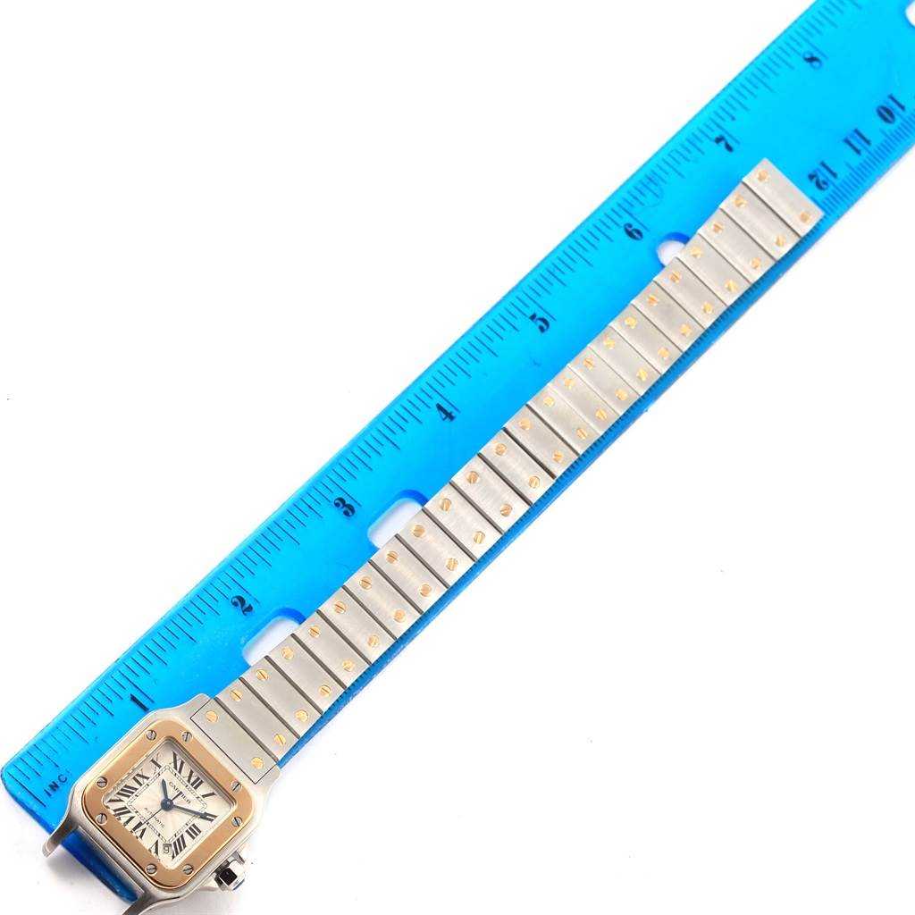 The image shows the entire face and bracelet of a Cartier Santos W20057C4 Women's Stainless Steel Silver Dial W20057C4 Women's Stainless Steel Silver Dial watch laid next to a blue ruler.