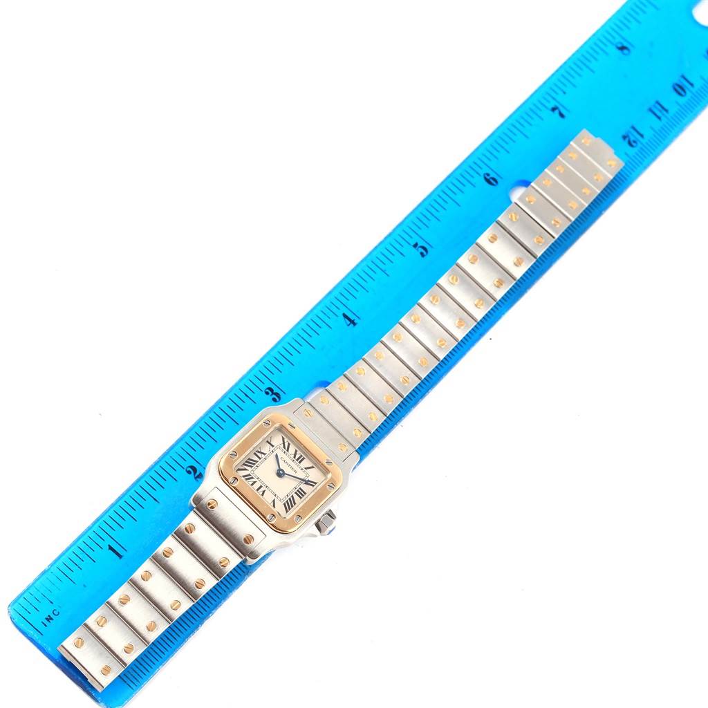 The Cartier Santos W20012C4 Women's Stainless Steel Silver Dial W20012C4 Women's Stainless Steel Silver Dial watch is shown flat, displaying the dial, bezel, and full-length bracelet beside a ruler.