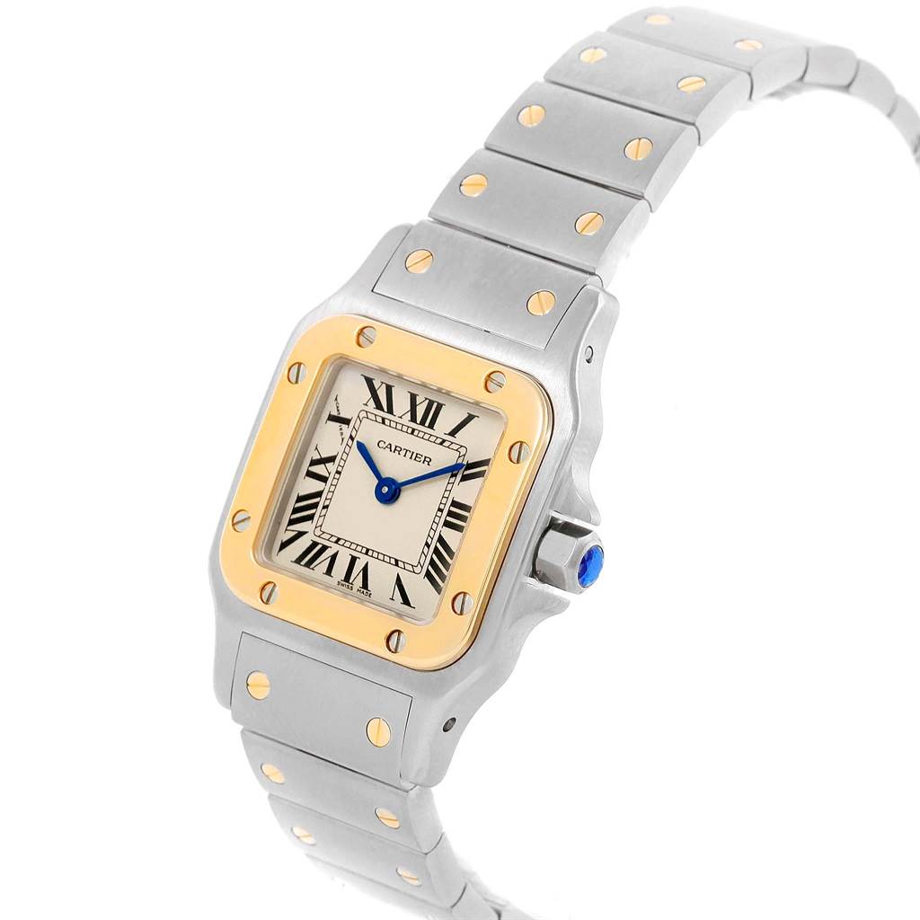 The image shows a Santos model watch by Cartier, focusing on the face and part of the metal strap at an angled view.
