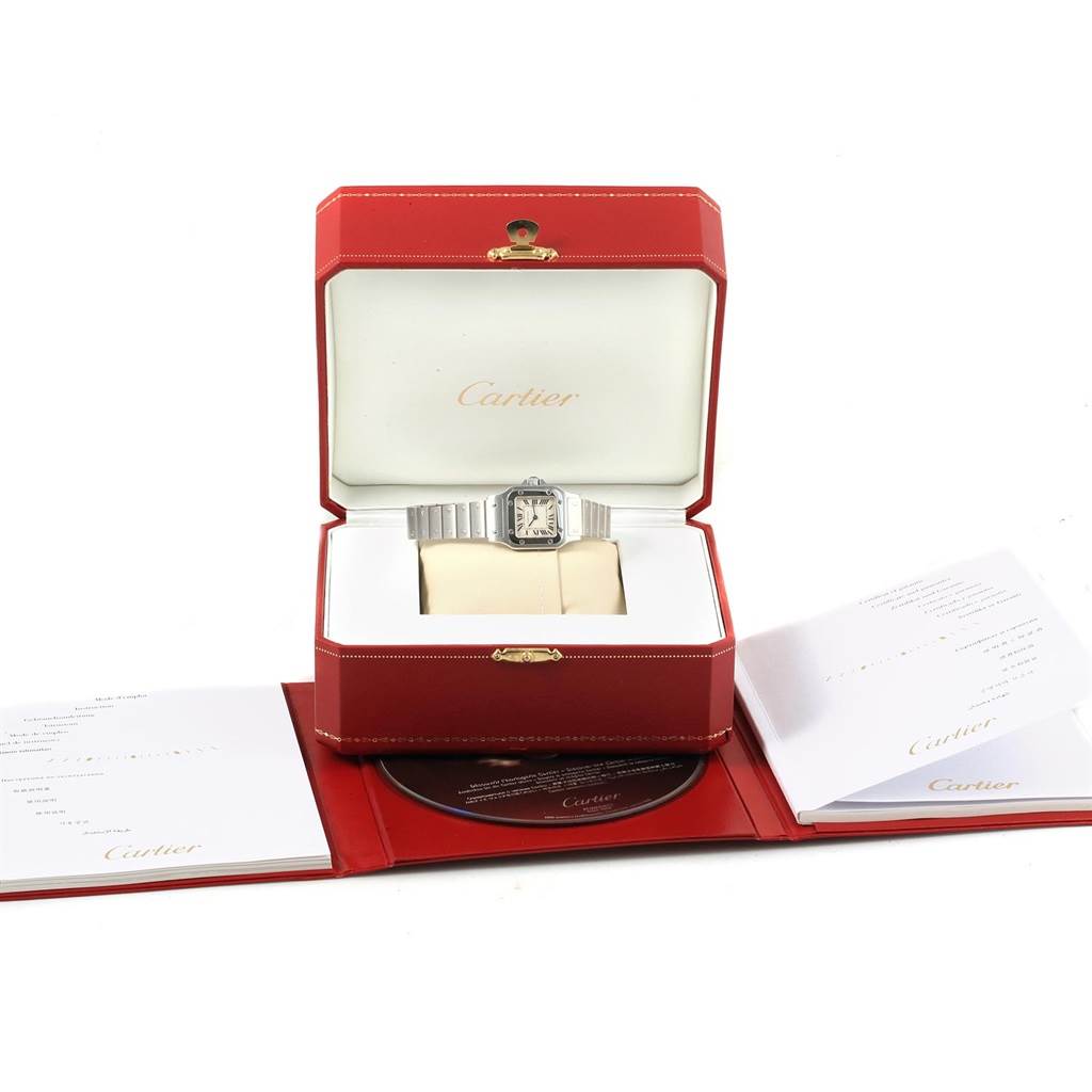 The Cartier Santos W20056D6 Women's Stainless Steel Silver Dial W20056D6 Women's Stainless Steel Silver Dial watch is displayed front-on in an open red box, with booklets and a CD next to it.