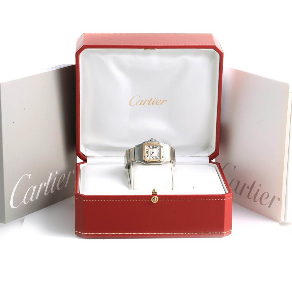 The Cartier Santos W20012C4 Women's Stainless Steel Silver Dial W20012C4 Women's Stainless Steel Silver Dial watch is displayed front-facing in a red Cartier box with its booklet accessories visible.