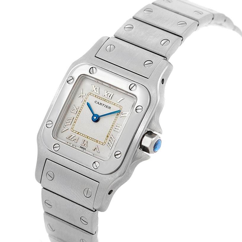 A Cartier Santos 1565 Women's Stainless Steel Silver Dial 1565 Women's Stainless Steel Silver Dial watch is shown at an angle displaying its face, Roman numerals, blue hands, bezel, and metal bracelet.