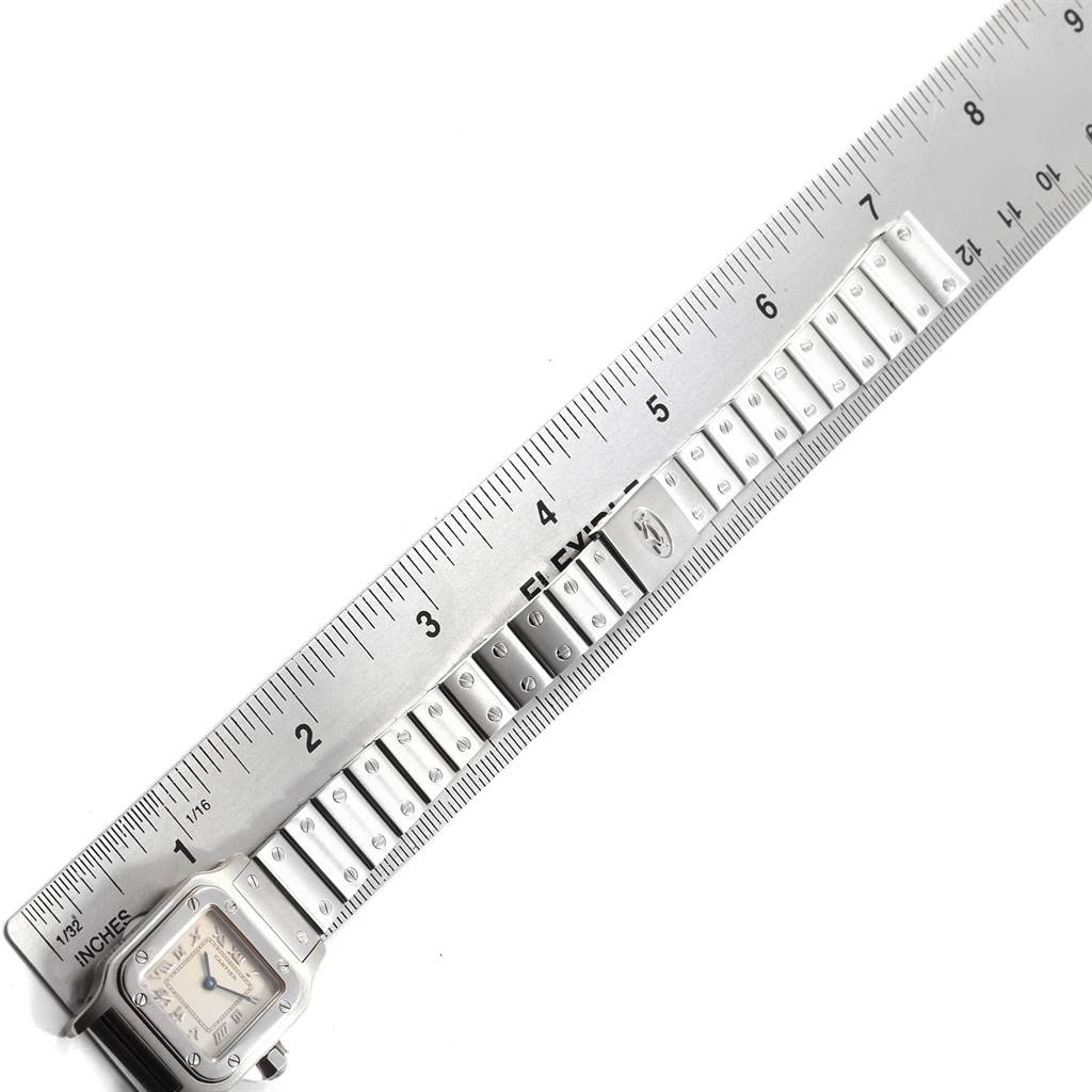 The image shows a Cartier Santos 1565 Women's Stainless Steel Silver Dial 1565 Women's Stainless Steel Silver Dial watch lying flat next to a ruler, displaying the face and partial bracelet.